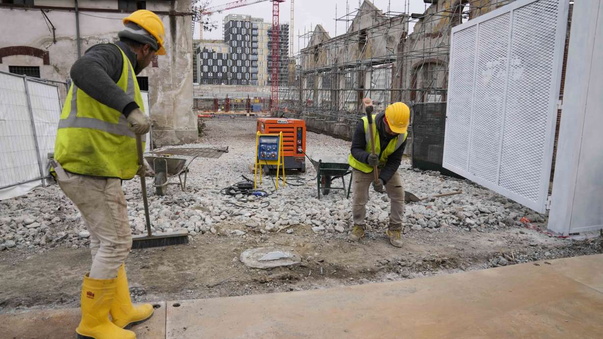 Workers operate inside the construction site of the Olympic Village at the Porta Romana former railway yard, in Milan, Italy, Wednesday, March 1, 2023. There is little sign the Winter Olympics are coming to Milan in less than three years. One of the major sites is still an overgrown wasteland and there is minimal construction work at what will be the Olympic Village. The organizing committee for the 2026 Milan-Cortina Olympics says there have been delays and rising costs.