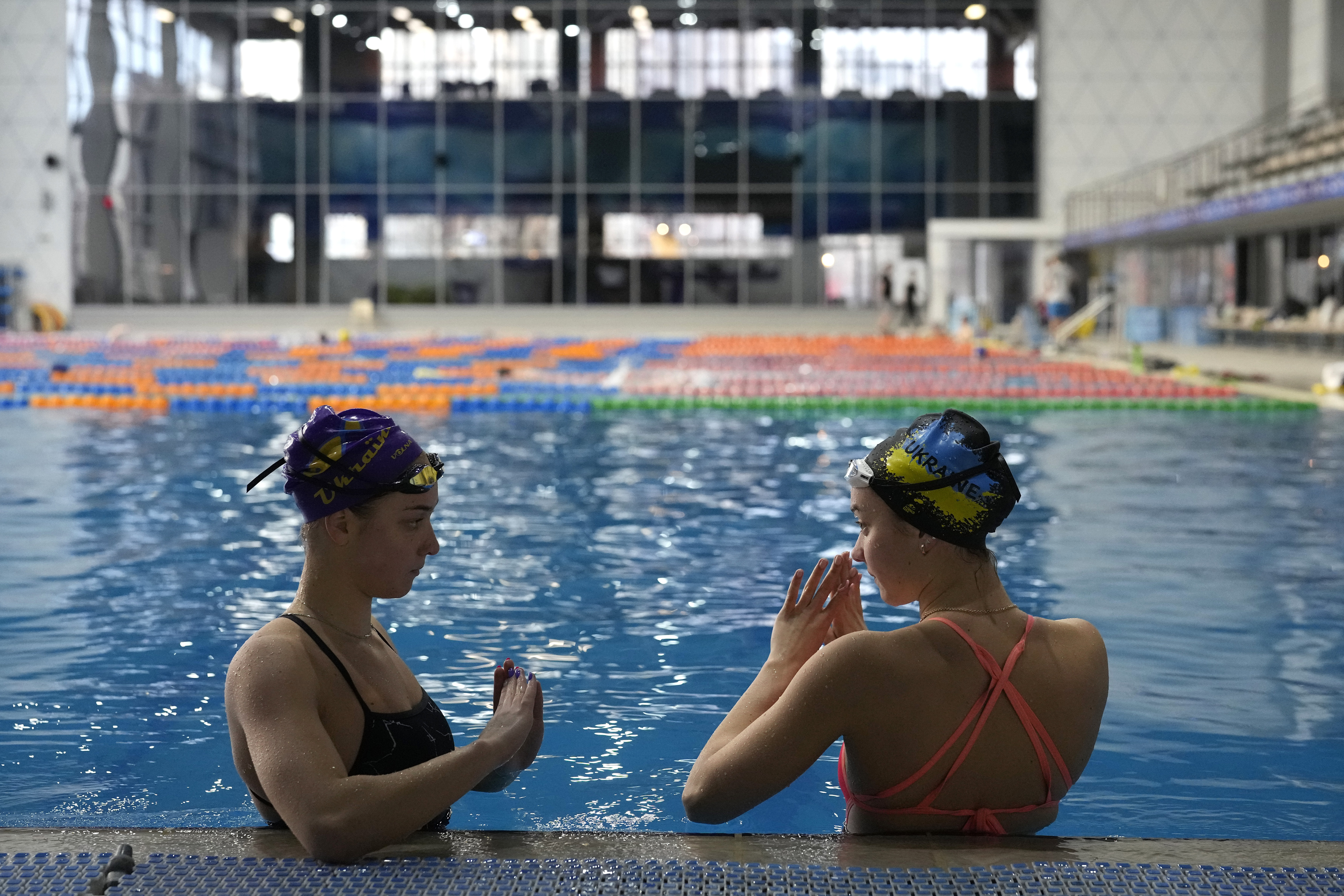Ukrainian sisters Maryna, left, and Vladyslava Aleksiiva speak during a practice session, in Kyiv, Ukraine, Tuesday, Feb. 21, 2023. The path to the 2024 Paris Olympics for Ukrainian athletes is clouded by war, anger and pain. Russian bombardments have wrecked training venues. Air raids disrupt training sessions. Athletes have lost family members and friends. Or they worry that they will. 