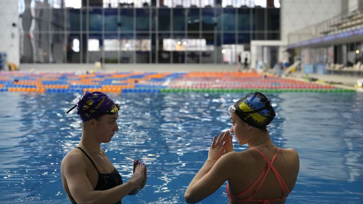 Ukrainian sisters Maryna, left, and Vladyslava Aleksiiva speak during a practice session, in Kyiv, Ukraine, Tuesday, Feb. 21, 2023. The path to the 2024 Paris Olympics for Ukrainian athletes is clouded by war, anger and pain. Russian bombardments have wrecked training venues. Air raids disrupt training sessions. Athletes have lost family members and friends. Or they worry that they will.