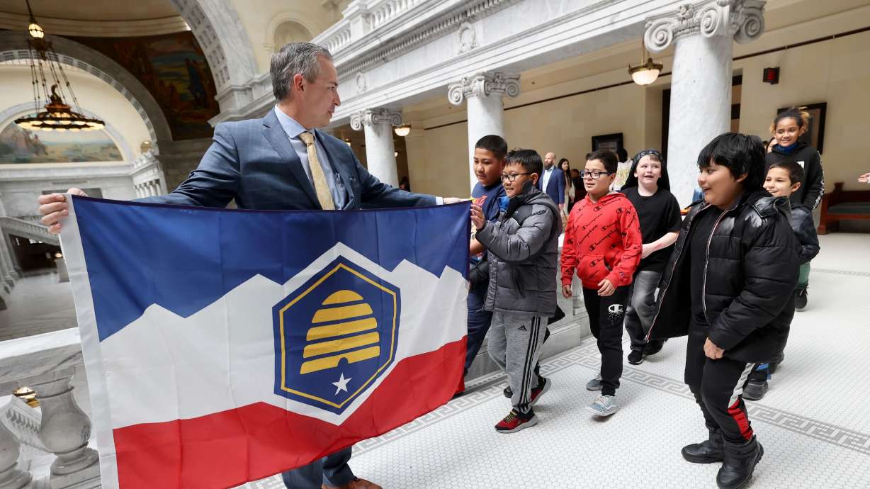 Sen. Dan McCay, R-Riverton, shows off a physical version of the new Utah state flag to Academy Park Elementary School fifth graders at the Utah Capitol Thursday afternoon. The Utah Legislature approved the design earlier in the day.