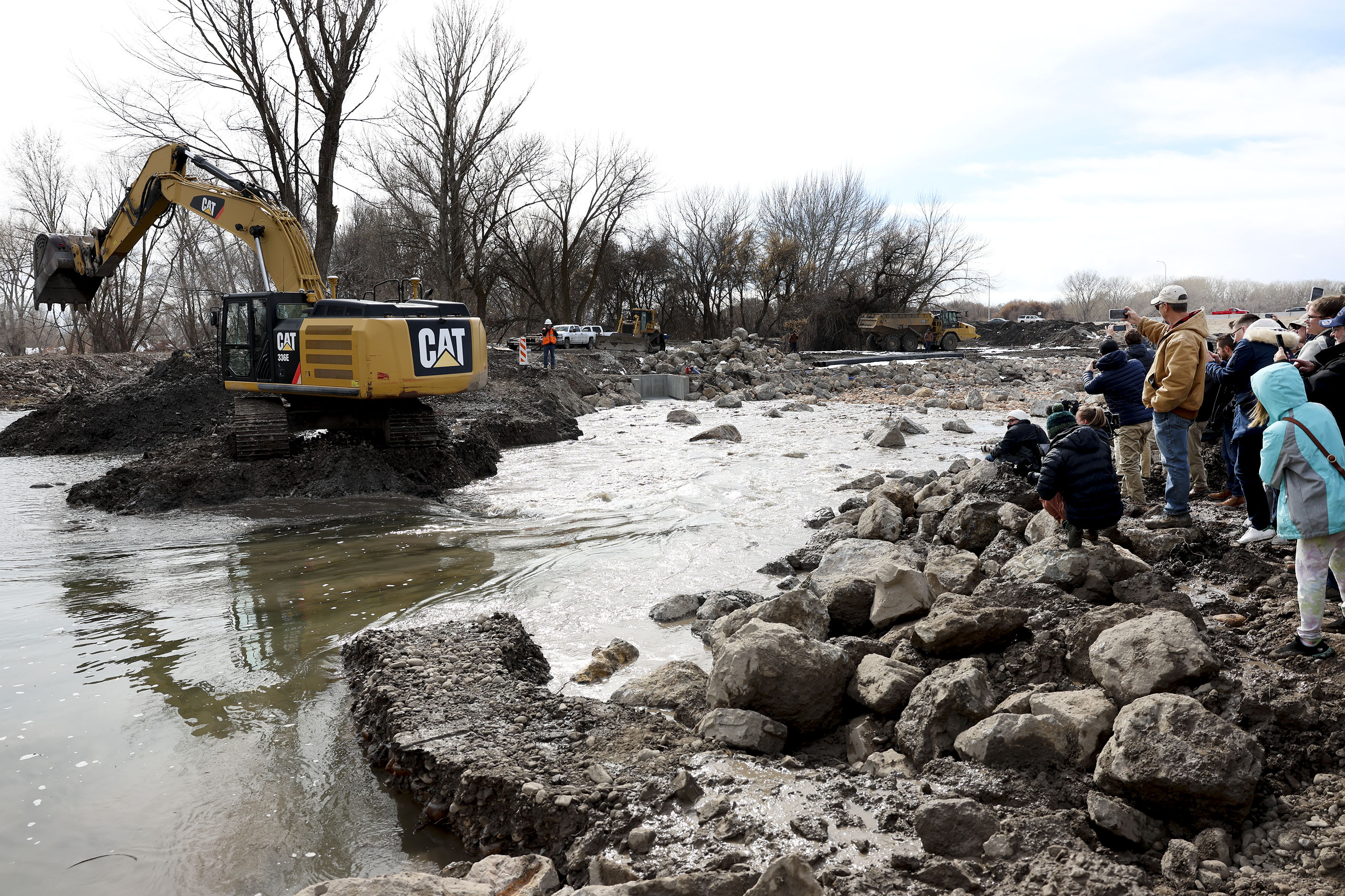 People watch as machinery clears a dam allowing the Provo River to be diverted into the Provo River Delta Restoration Project area in Provo on Thursday.