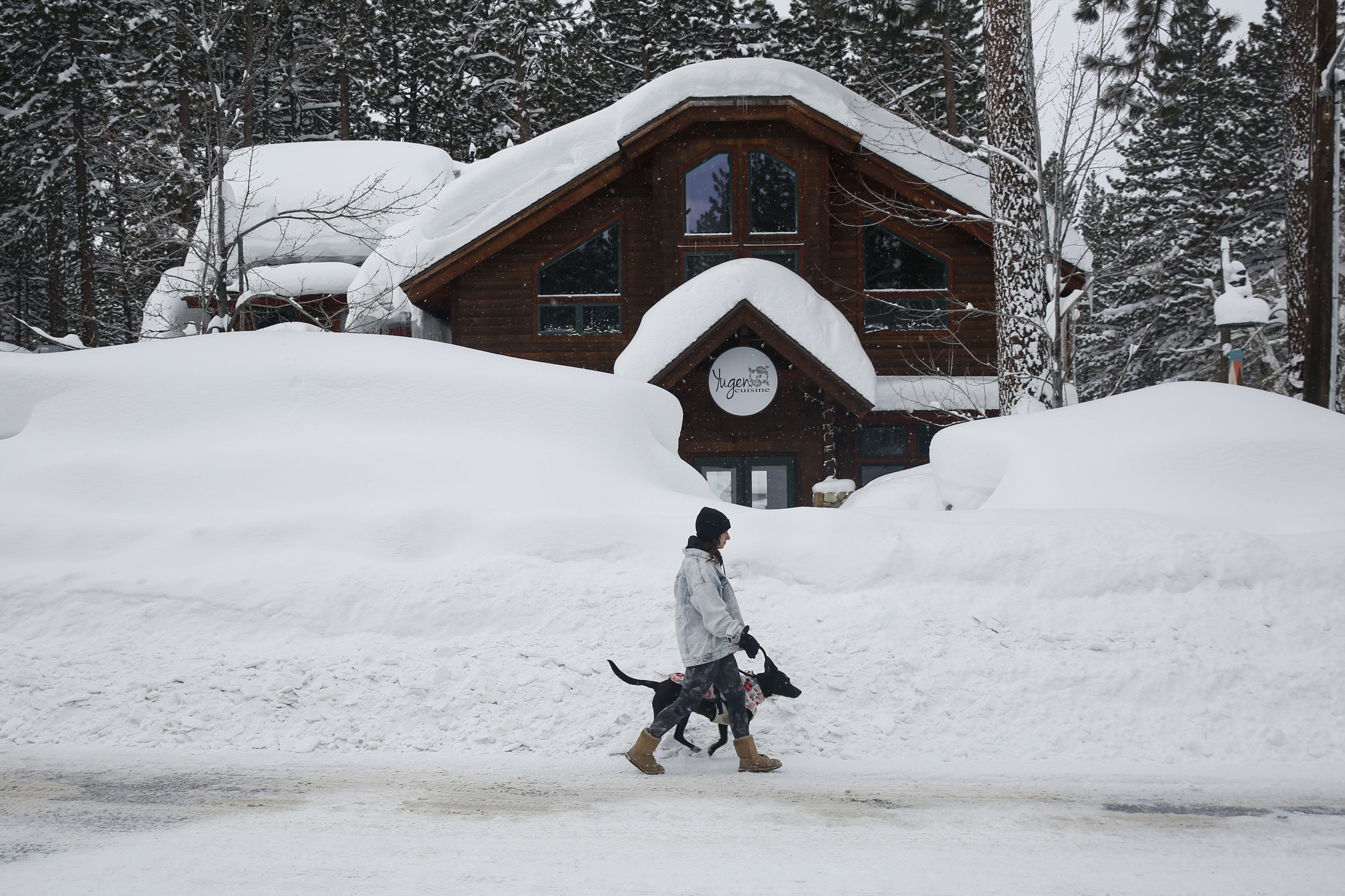 Resident Laurene Bishop walks her dog Aubrey down Ski Run Boulevard in South Lake Tahoe, Calif., on Wednesday, March 1. Snow accumulation totals in the Sierra Nevadas are on record pace.