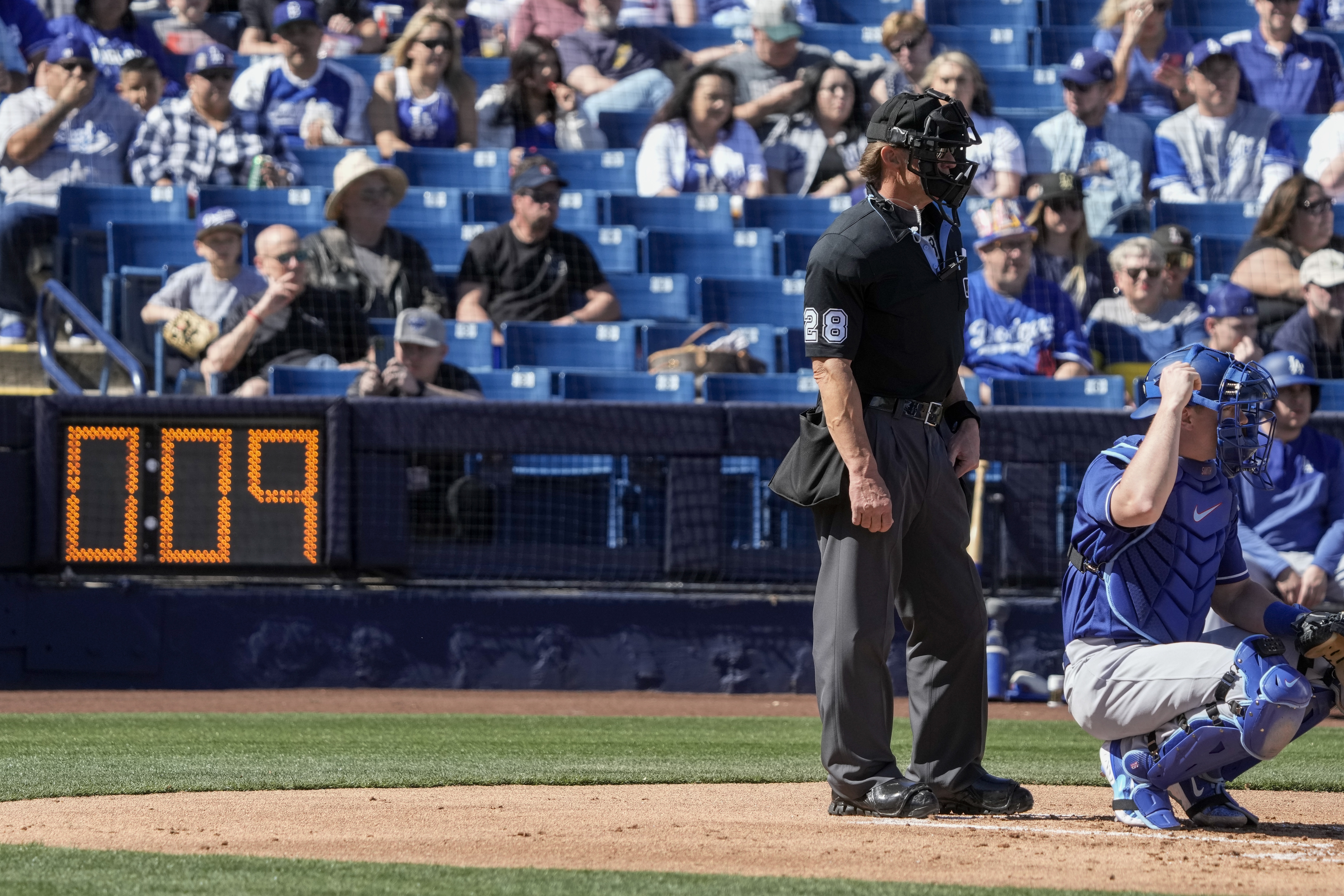 Home plate umpire Jim Wolf waits as the pitch clock counts down during the first inning of a spring training baseball game between the Milwaukee Brewers and the Los Angeles Dodgers Saturday, Feb. 25, 2023, in Phoenix.