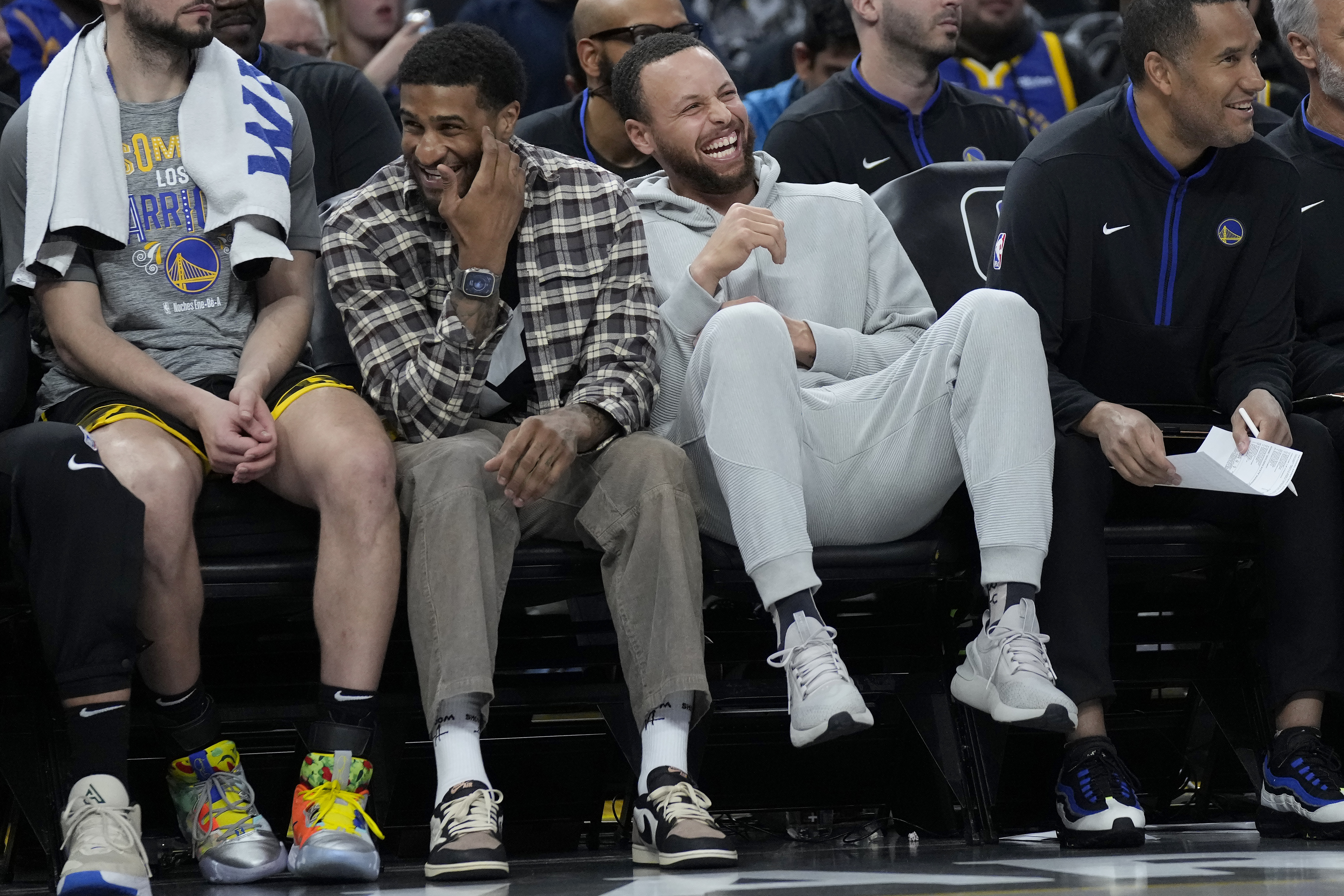Golden State Warriors' Gary Payton II, middle left, laughs on the bench next to Stephen Curry during the first half of the team's NBA basketball game against the Los Angeles Clippers in San Francisco, Thursday, March 2, 2023. 