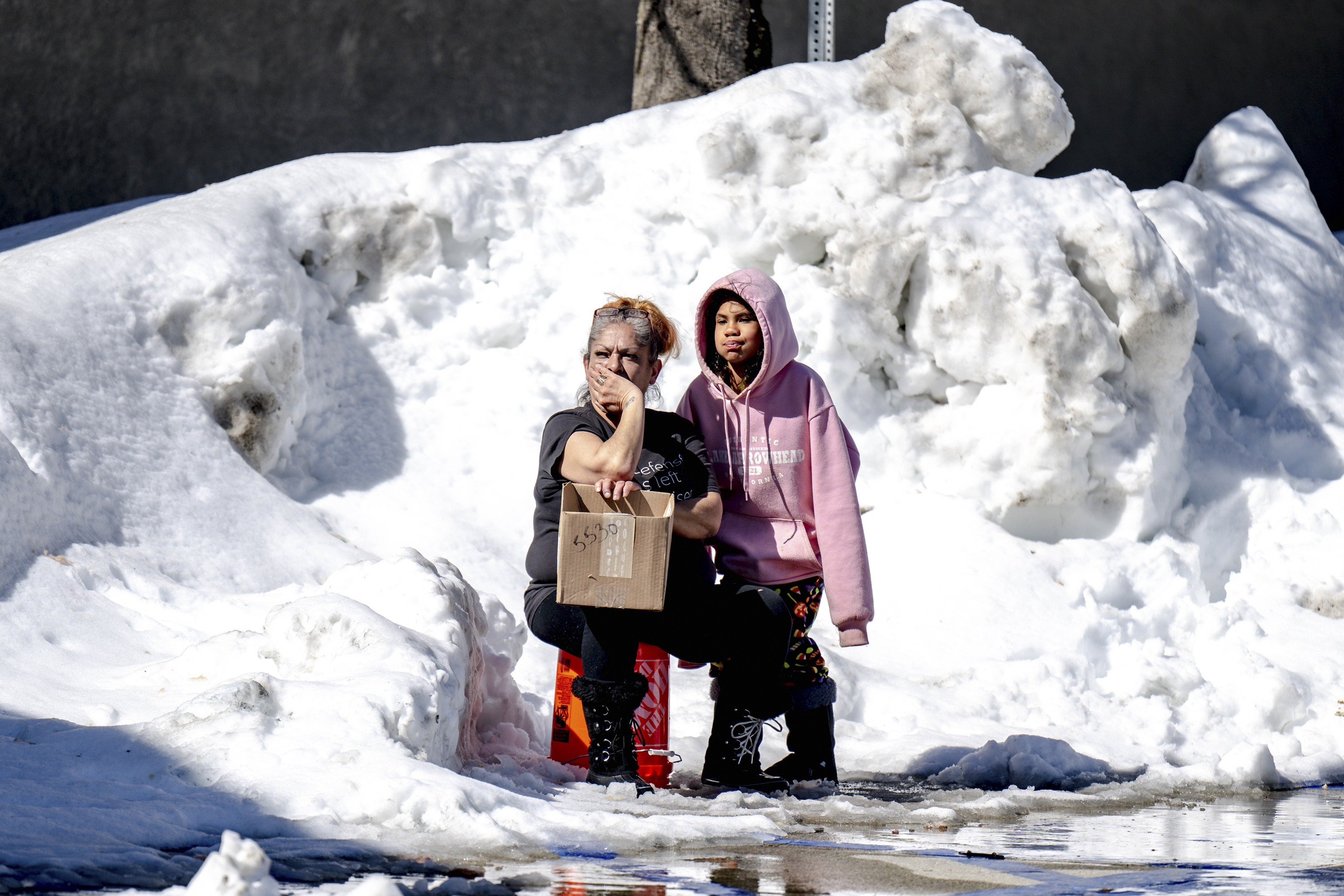 People wait for food at Goodwin & Son's Market in Crestline, Calif., Friday. Some residents remain trapped by heavy snowfall.
