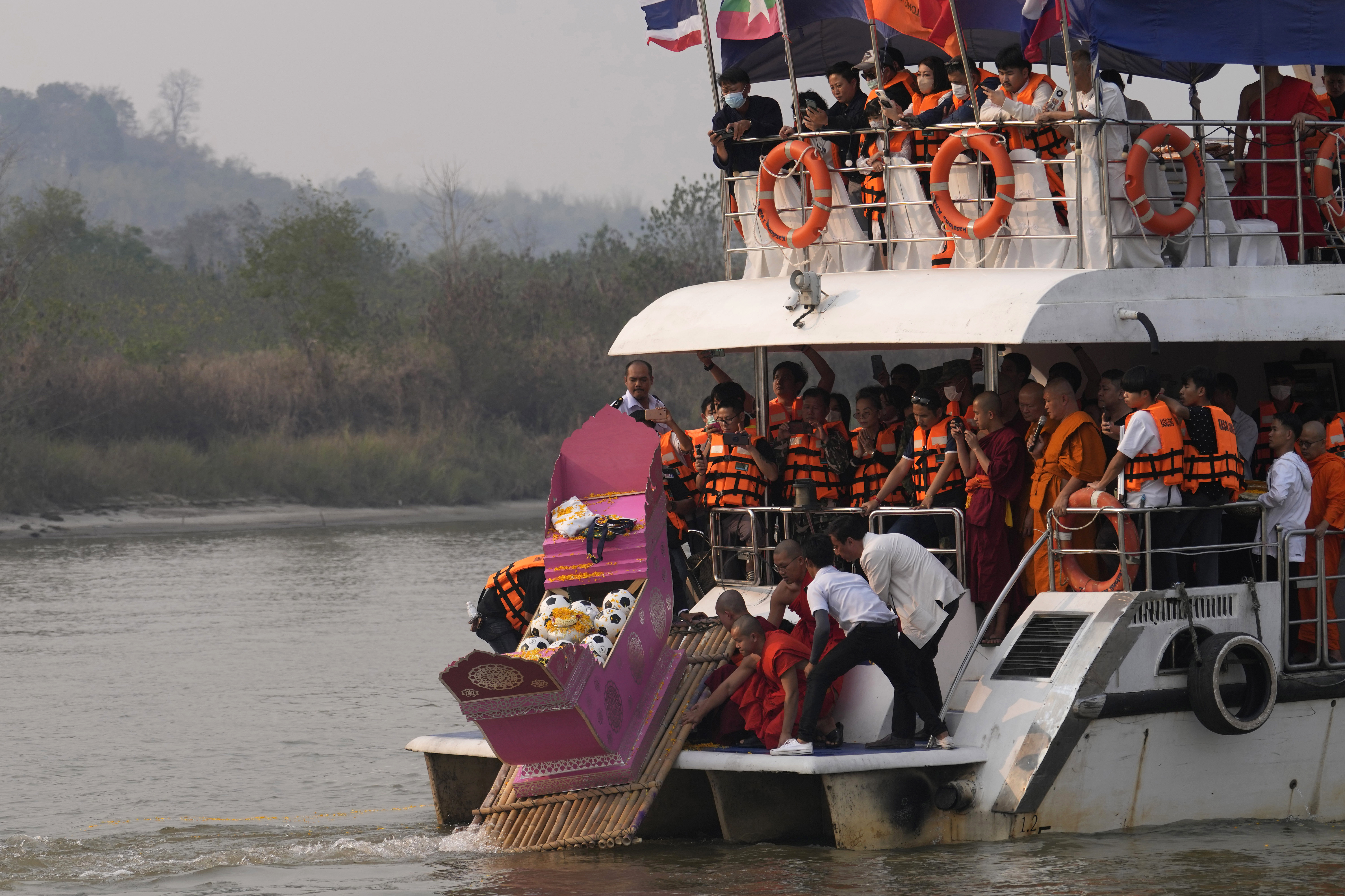 Family members, accompanied by monks and fellow mourners, release the ashes of Duangphet Phromthep in a makeshift boat along with soccer balls and some of his prized possessions into the Mekong River in Chiang Rai Province Thailand, Monday, March 6, 2023. Duangphet was one of the 12 boys rescued from a flooded cave in 2018. He died in the U.K. last month. 