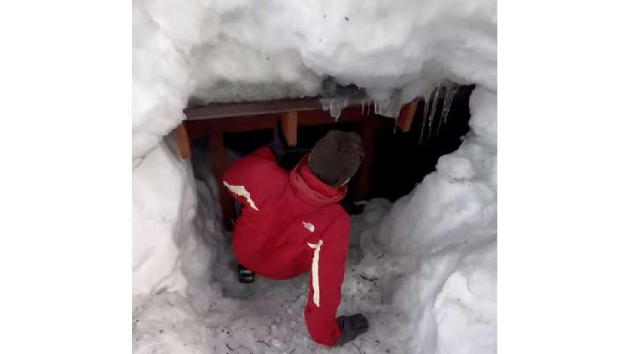 A man slides onto his front porch, which is completely buried by snow in Lake Tahoe, California.