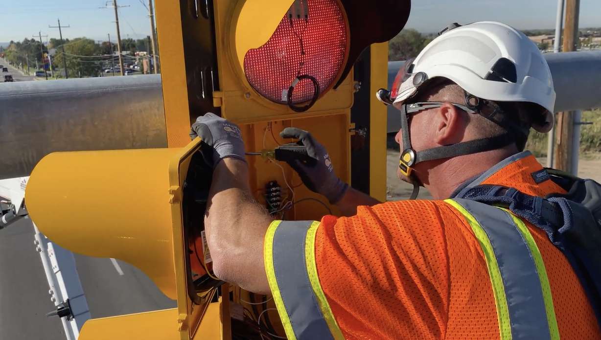 A Utah Department of Transportation engineer configures heat tape wiring onto a traffic signal in Utah. UDOT began testing the system a few years ago before expanding it to lights across the state.