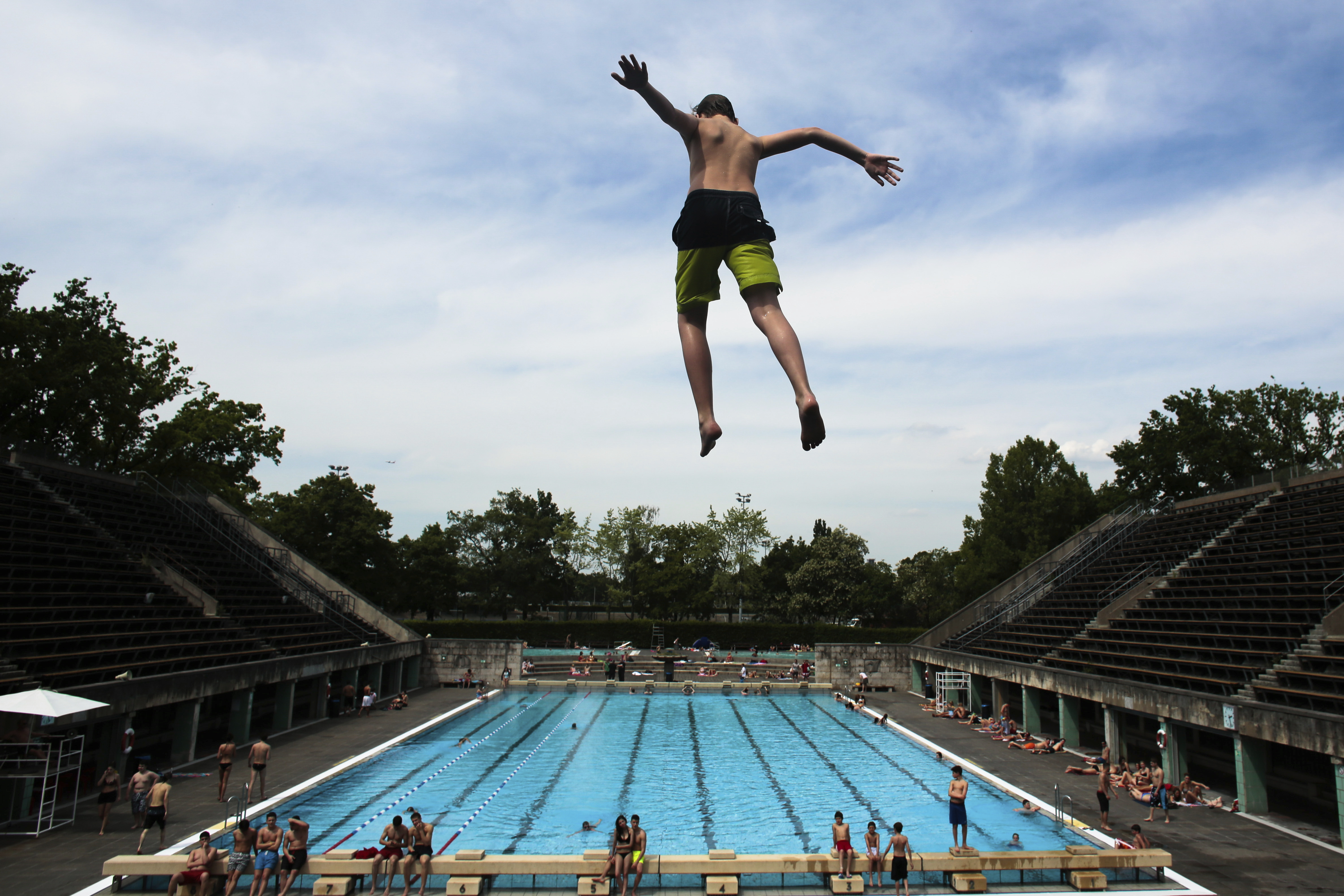 A boy jumps into the water at the Olympic open air public pool in Berlin, Germany, May 21, 2014. Women in Berlin will soon be allowed to go topless at the city's public pools, the Berlin state government said Thursday. The new bathing rules to allow both men and women to go swimming without covering their upper bodies came in reaction to a woman's complaint alleging discrimination because she was not allowed to swim topless in a swimming pool in Berlin, like men. 