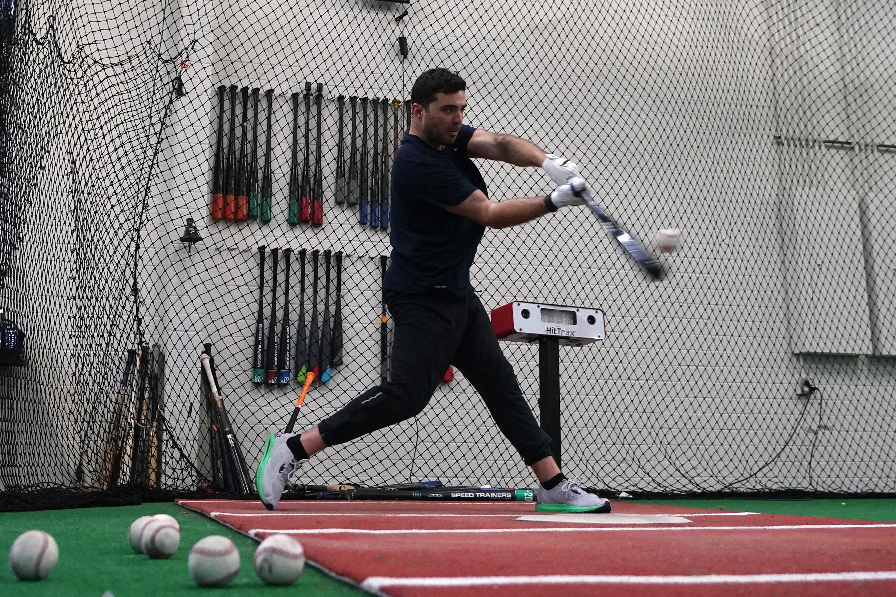 A batter takes a swing inside a batting cage at the Driveline facility in Scottsdale, Ariz., Thursday, Feb. 16, 2023. The batting information is read by a sensor device just to the right of the batter and the information is projected onto the screen in a different part of the cage area. 