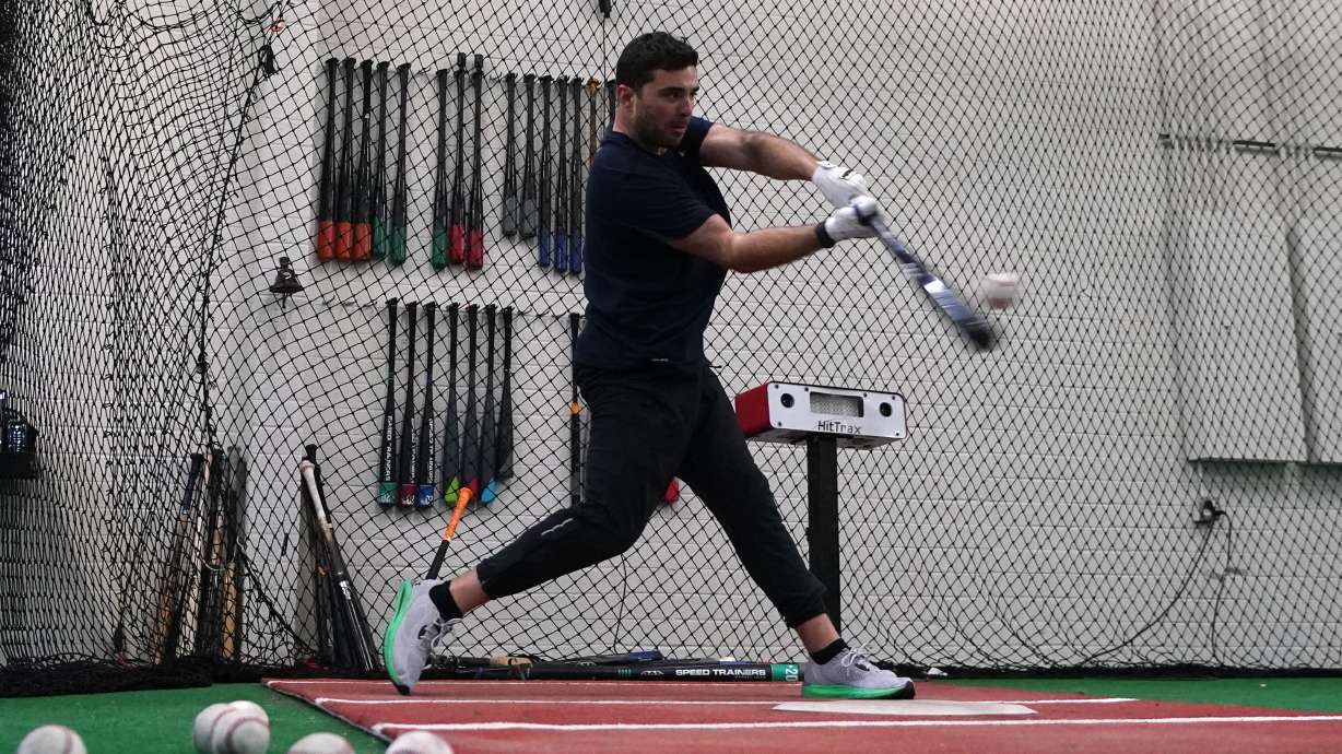 A batter takes a swing inside a batting cage at the Driveline facility in Scottsdale, Ariz., Thursday, Feb. 16, 2023. The batting information is read by a sensor device just to the right of the batter and the information is projected onto the screen in a different part of the cage area.