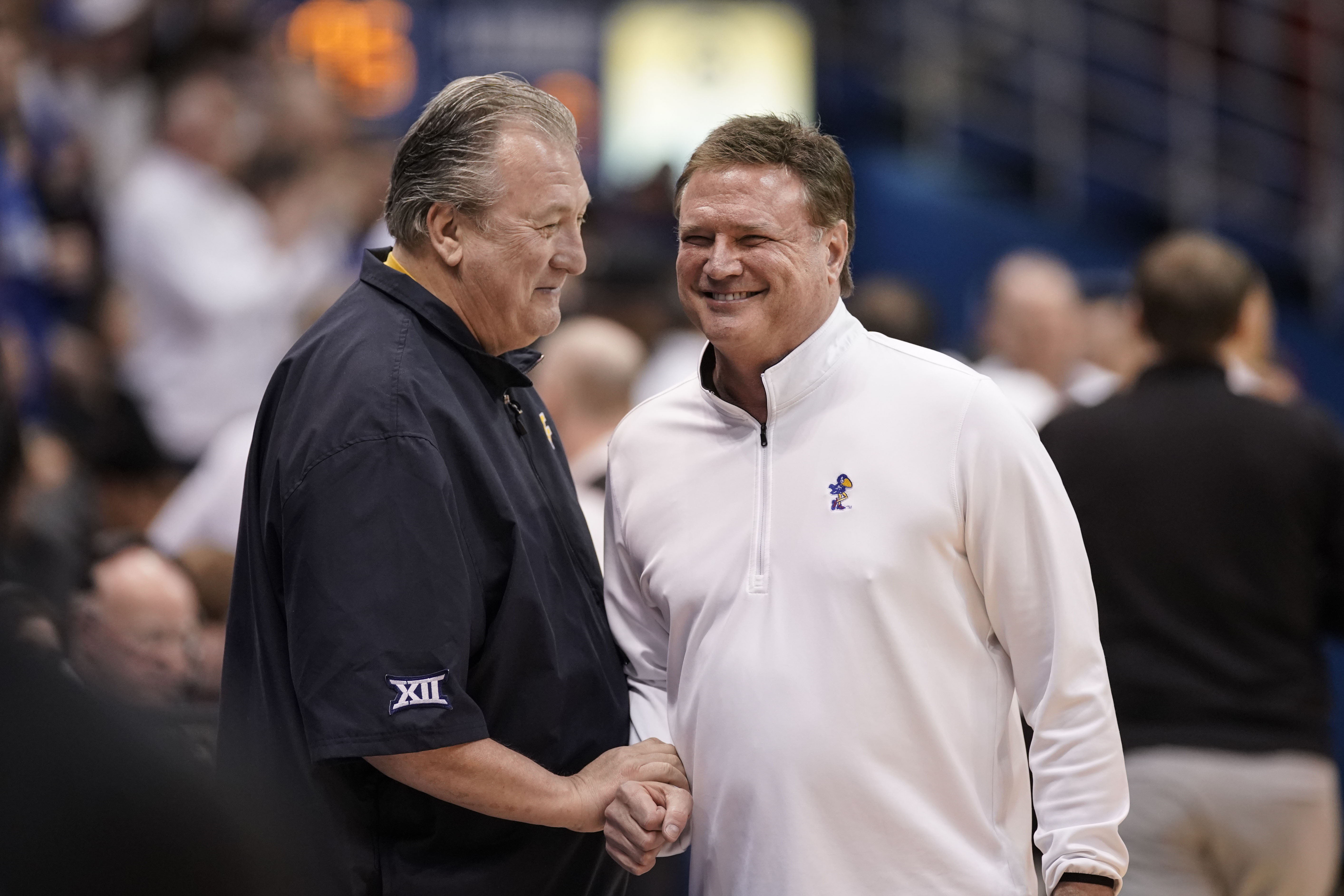 West Virginia head coach Bob Huggins, left, and Kansas head coach Bill Self have a laugh before tipoff of an NCAA college basketball game on Saturday, Feb. 25, 2023, at Allen Fieldhouse in Lawrence, Kan.