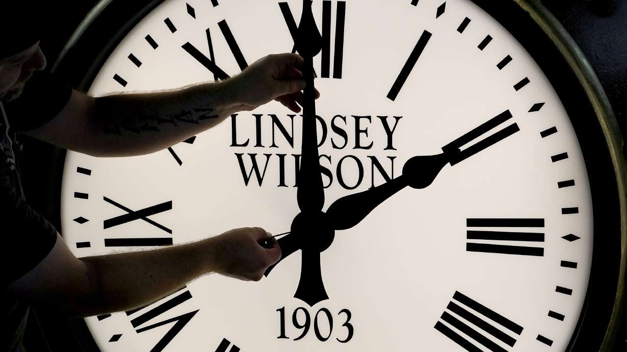 Dan LaMoore adjusts the hands on a Seth Thomas Post Clock at Electric Time Company, Oct. 23, 2020, in Medfield, Mass. Standard time comes to an end in most parts of the United States this weekend. You’ll lose an hour of sleep for one night but gain more daylight in the evening in the months ahead.