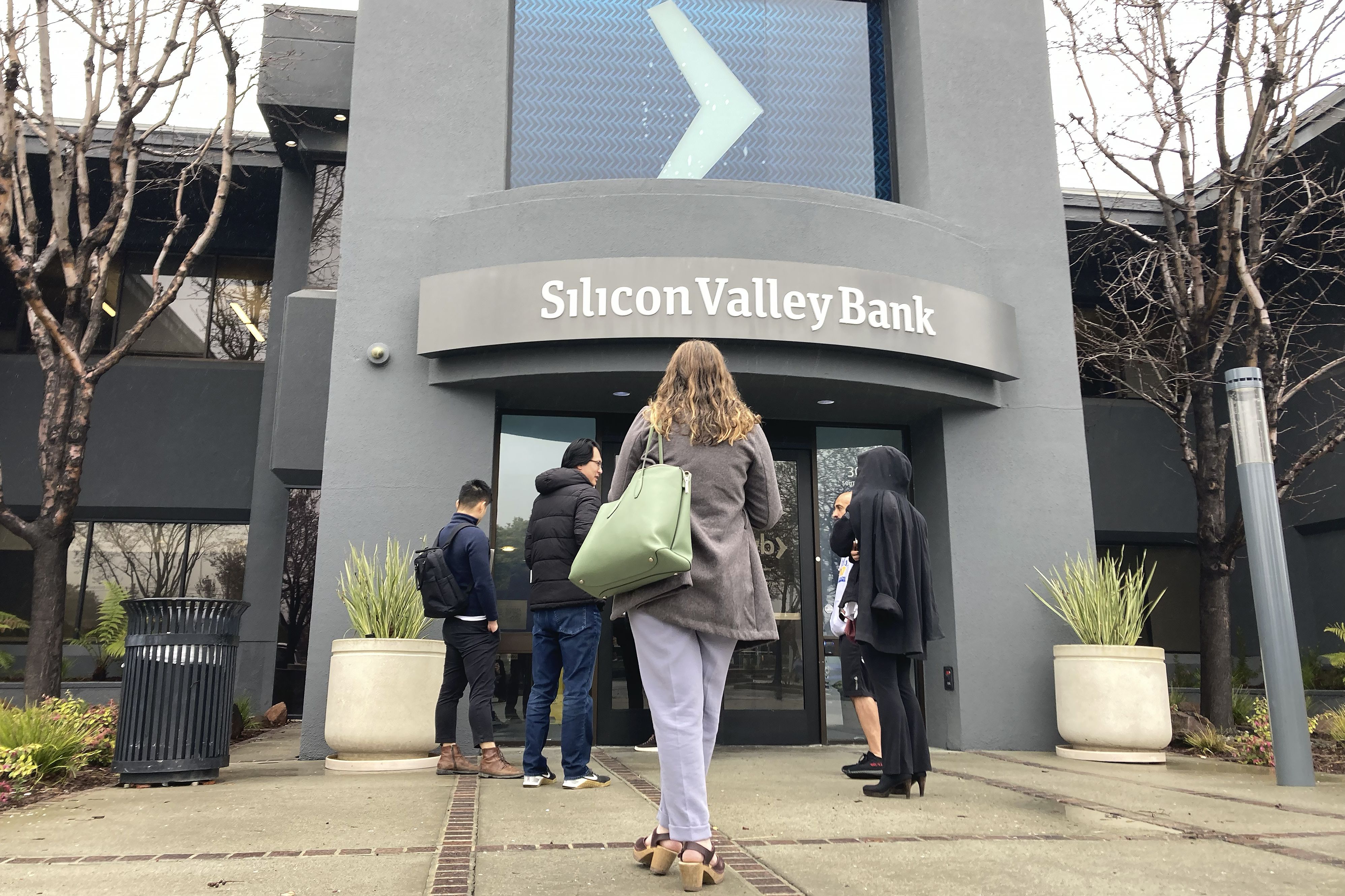 People stand outside of an entrance to Silicon Valley Bank in Santa Clara, Calif., Friday. The Federal Deposit Insurance Corporation seized the assets of the bank on Friday, marking the largest bank failure since Washington Mutual during the height of the 2008 financial crisis.