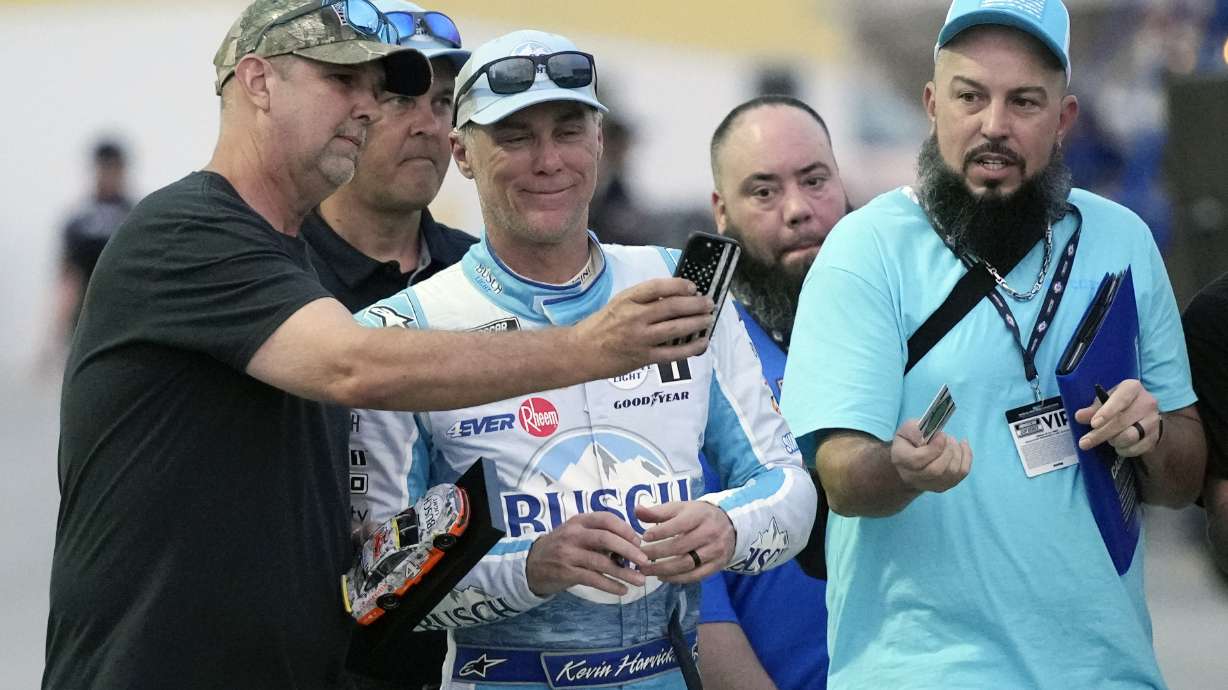 Fans takes selfie photos with Kevin Harvick, center, in the garage area during a practice session for the NASCAR Daytona 500 auto race at Daytona International Speedway, Friday, Feb. 17, 2023, in Daytona Beach, Fla.