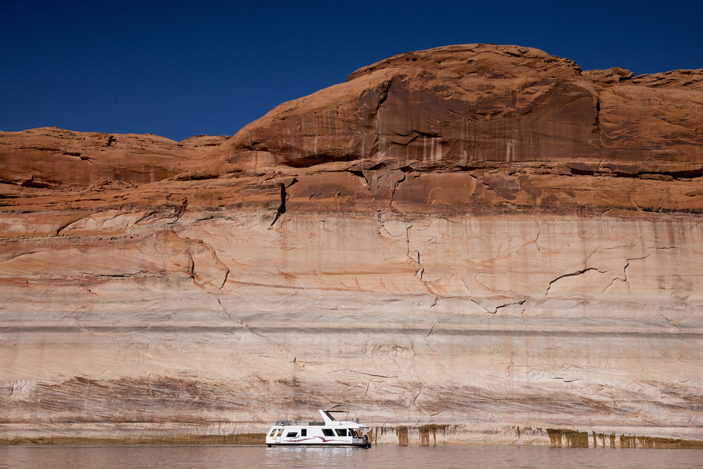 A houseboat is seen against the backdrop of Lake Powell’s “bathtub ring,” a light-colored coating of mineral deposits left on the canyon walls during periods of higher water in the reservoir, on Oct. 6, 2022 near Bullfrog. At the time, the surface of the reservoir was approximately 170 feet below “full pool.”