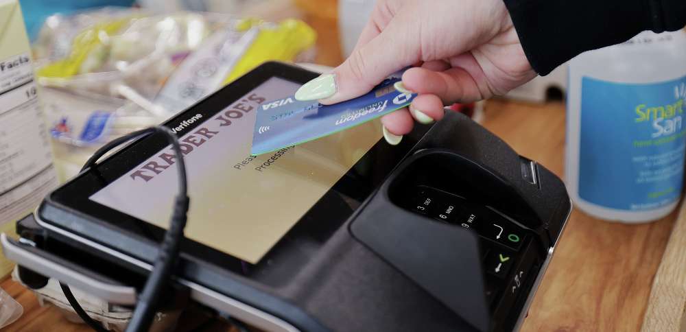 A woman uses her card to make her purchase at Trader Joe’s in Draper on March 3. Annual inflation ticked down in February but prices were up over January.
