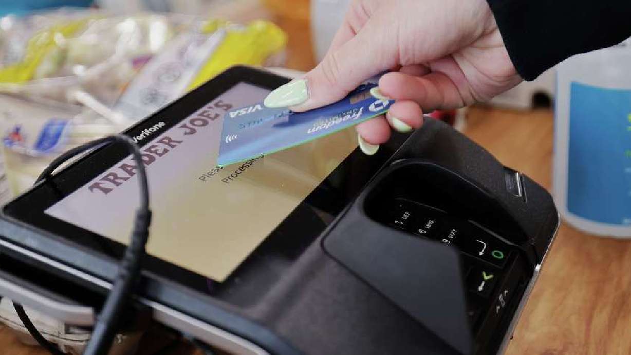 A woman uses her card to make her purchase at Trader Joe’s in Draper on March 3. Annual inflation ticked down in February but prices were up over January.
