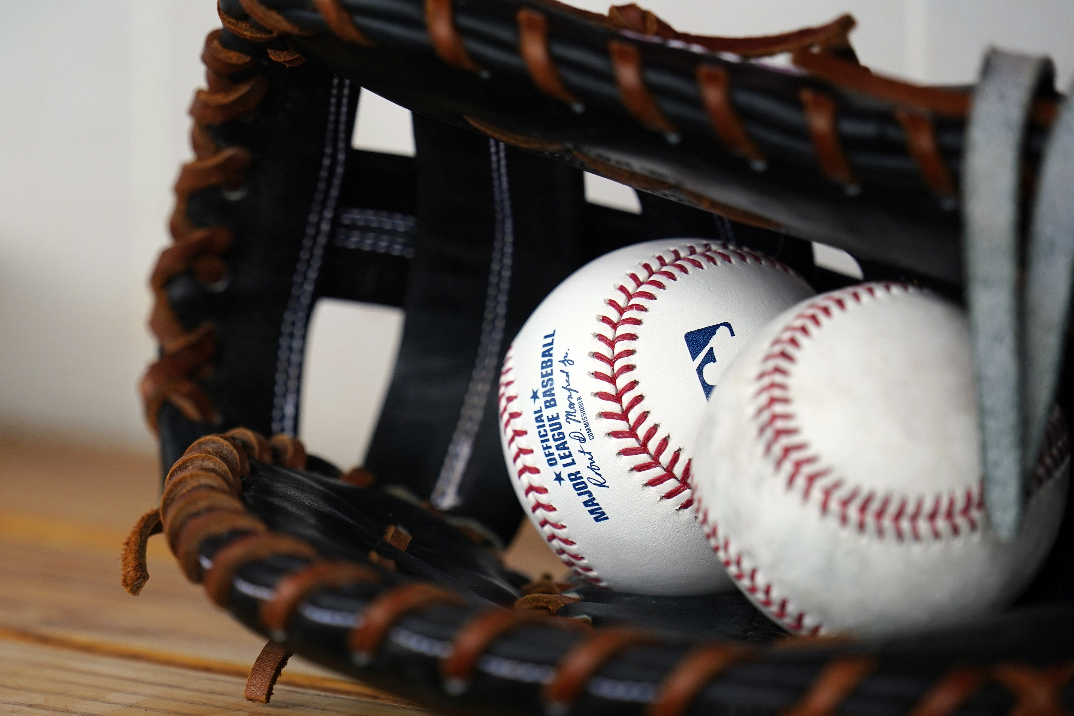 FILE - A pair baseballs and a glove sit in the Milwaukee Brewers dugout prior to a spring training baseball game against the Cleveland Guardians on March 29, 2022, in Goodyear, Ariz. Major League Baseball is heightening in-game inspections by umpires for banned grip aides, concerned use of foreign substances by pitchers increased again as time passed from start of a crackdown in June 2021.