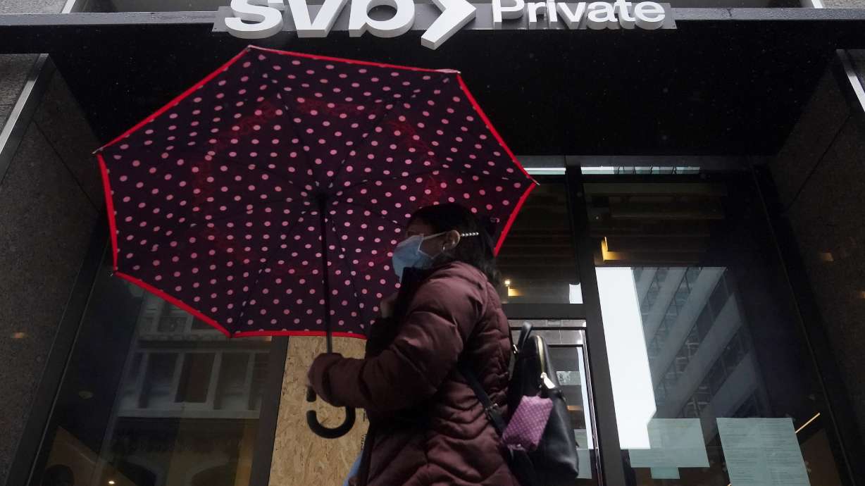 A pedestrian carries an umbrella while walking past a Silicon Valley Bank Private branch in San Francisco, Tuesday.