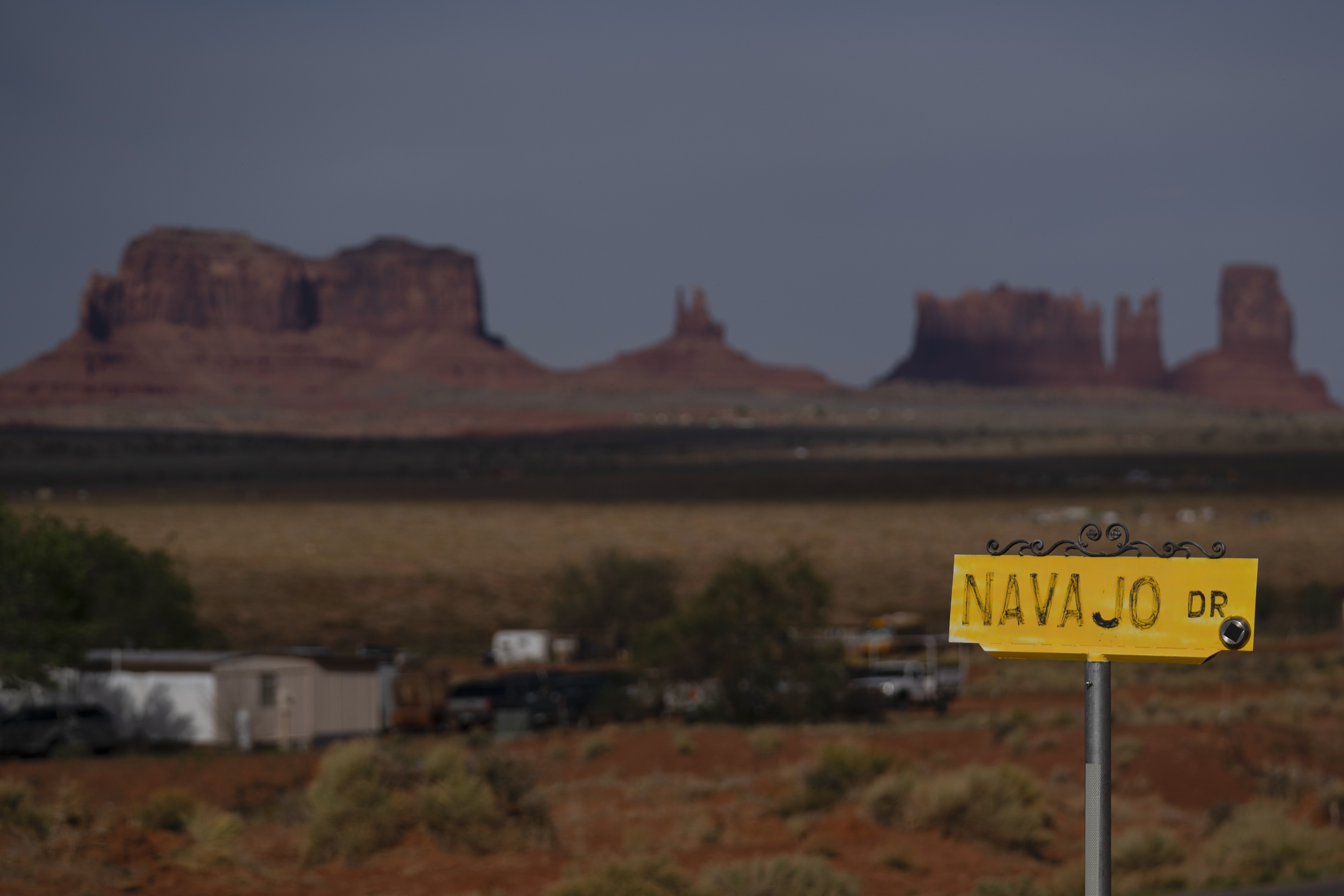 A sign marks Navajo Drive, as Sentinel Mesa, homes and other structures in Oljato-Monument Valley, Utah, on the Navajo Reservation, stand in the distance, on April 30, 2020. The U.S. Supreme Court will soon decide a critical water rights case in the water-scarce Southwest.