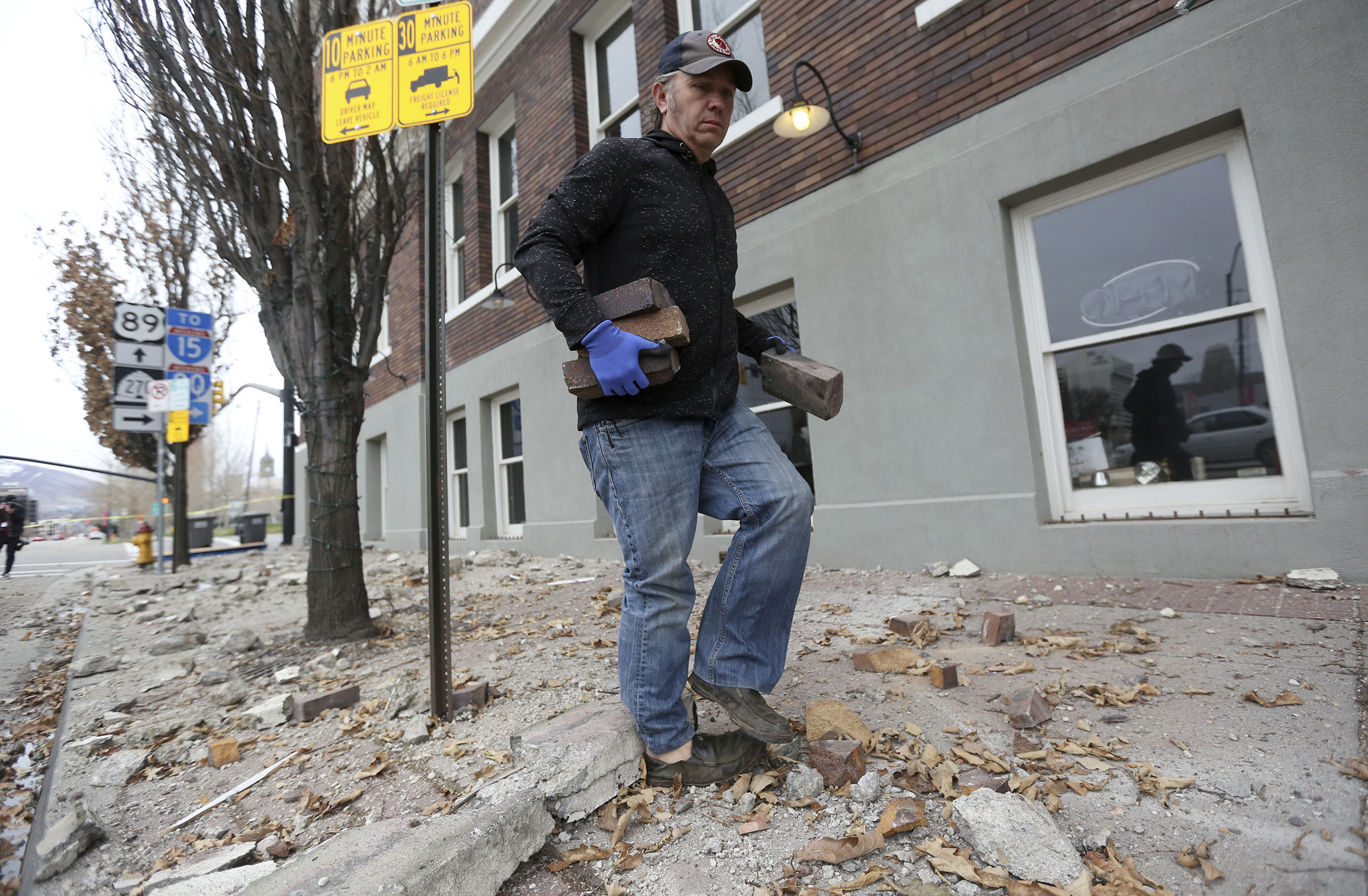 Fred Moesinger, owner of BTG Wine Bar and Caffe Molise in Salt Lake City, picks up bricks among debris that fell from his building after a 5.7 magnitude earthquake centered in Magna hit early on March 18, 2020.
