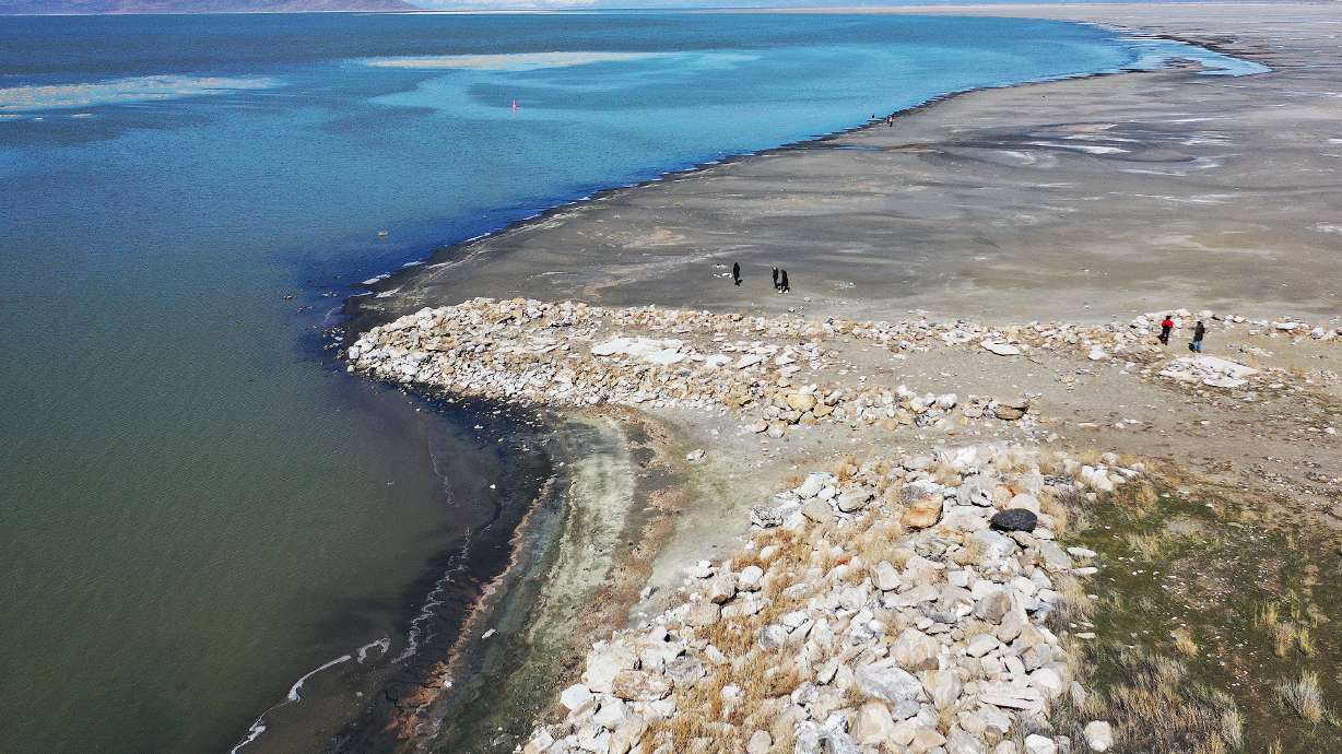 People walk on the beach of the Great Salt Lake in Salt Lake City on Friday. The Great Salt Lake is on the verge of collapse due to climate change, drought and population pressures.