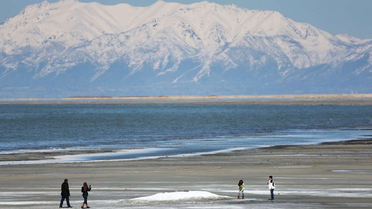 People walk on the beach of the Great Salt Lake in Salt Lake City on Friday. One of the world’s largest hypersaline lakes, the Great Salt Lake is on the verge of collapse due to climate change, drought and population pressures that have reduced inflows and shrunk the lake by more than two-thirds.
