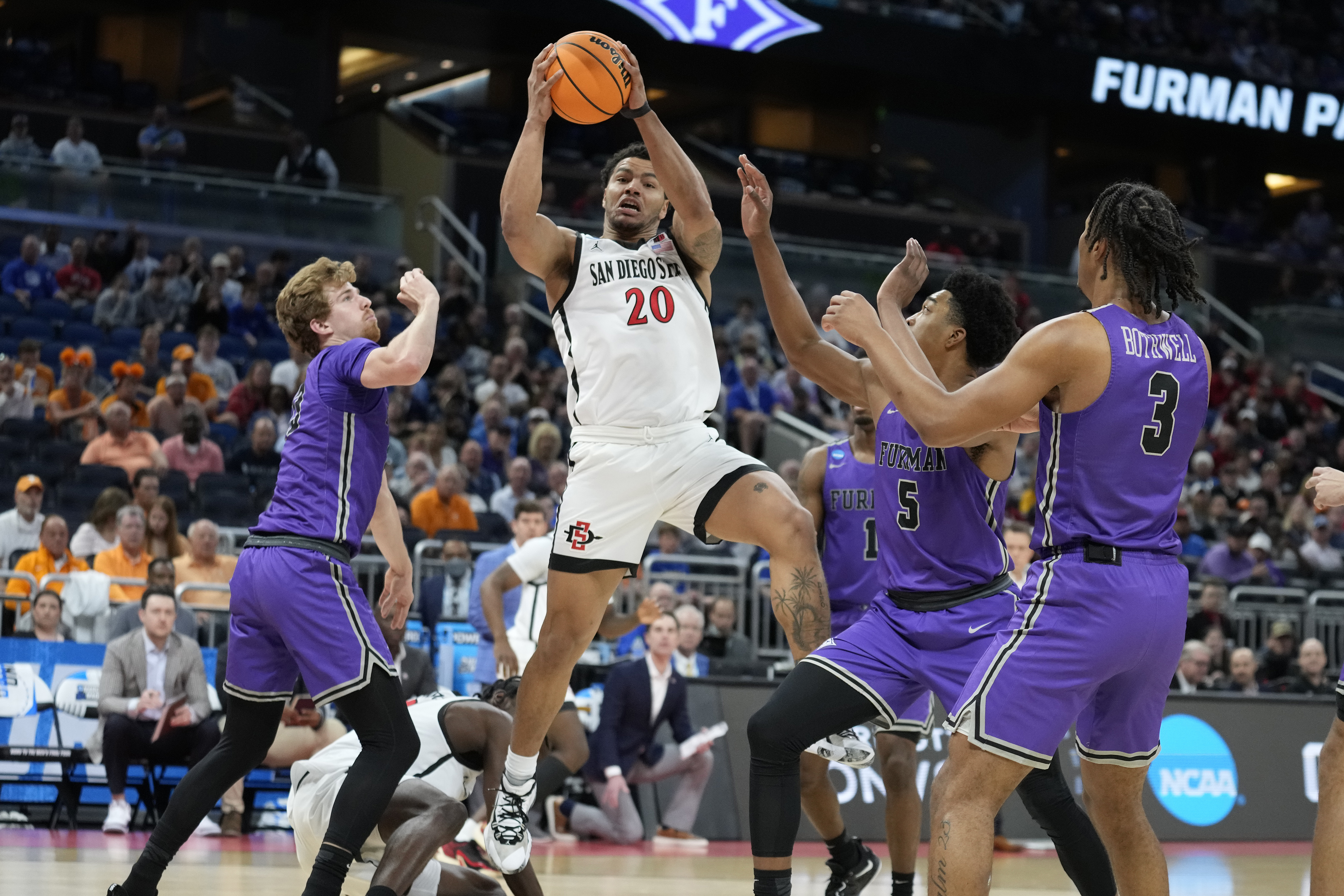 San Diego State guard Matt Bradley (20) grabs a rebound away from Furman forward Garrett Hien (13), guard Mike Bothwell (3) and guard Marcus Foster (5) during the first half of a second-round college basketball game in the NCAA Tournament Saturday, March 18, 2023, in Orlando, Fla. 