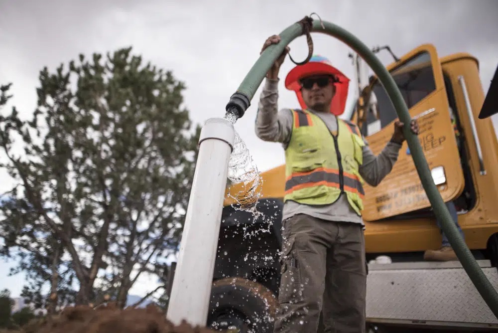 Donovan Smallcanyon, lead water and solar technician for the Navajo Mountain team of DigDeep's Navajo Water Project, fills the 1,200-gallon tank of a home water system, the organization's solution for off-grid homes, at a house in October 2022, near Navajo Mountain, Ariz.
