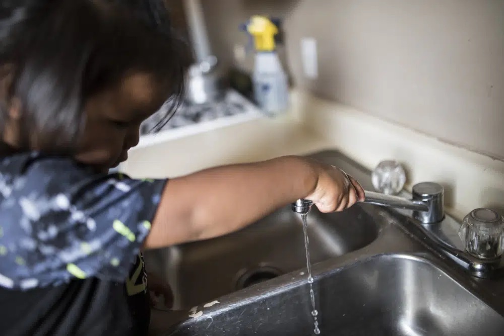 A child turns on a tap that was newly installed by nonprofit DigDeep in a home in October 2022, near Navajo Mountain, Ariz.