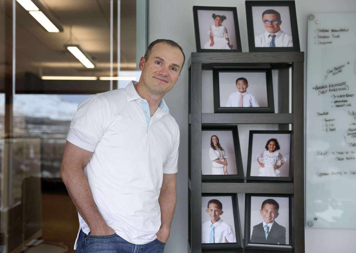 Brady Murray stands next to photographs of his seven children in his office in Lehi on March 10. Murray is the founder and president of Racing for Orphans with Down Syndrome (RODS Racing), a nonprofit dedicated to helping orphaned children who have Down syndrome find loving homes.