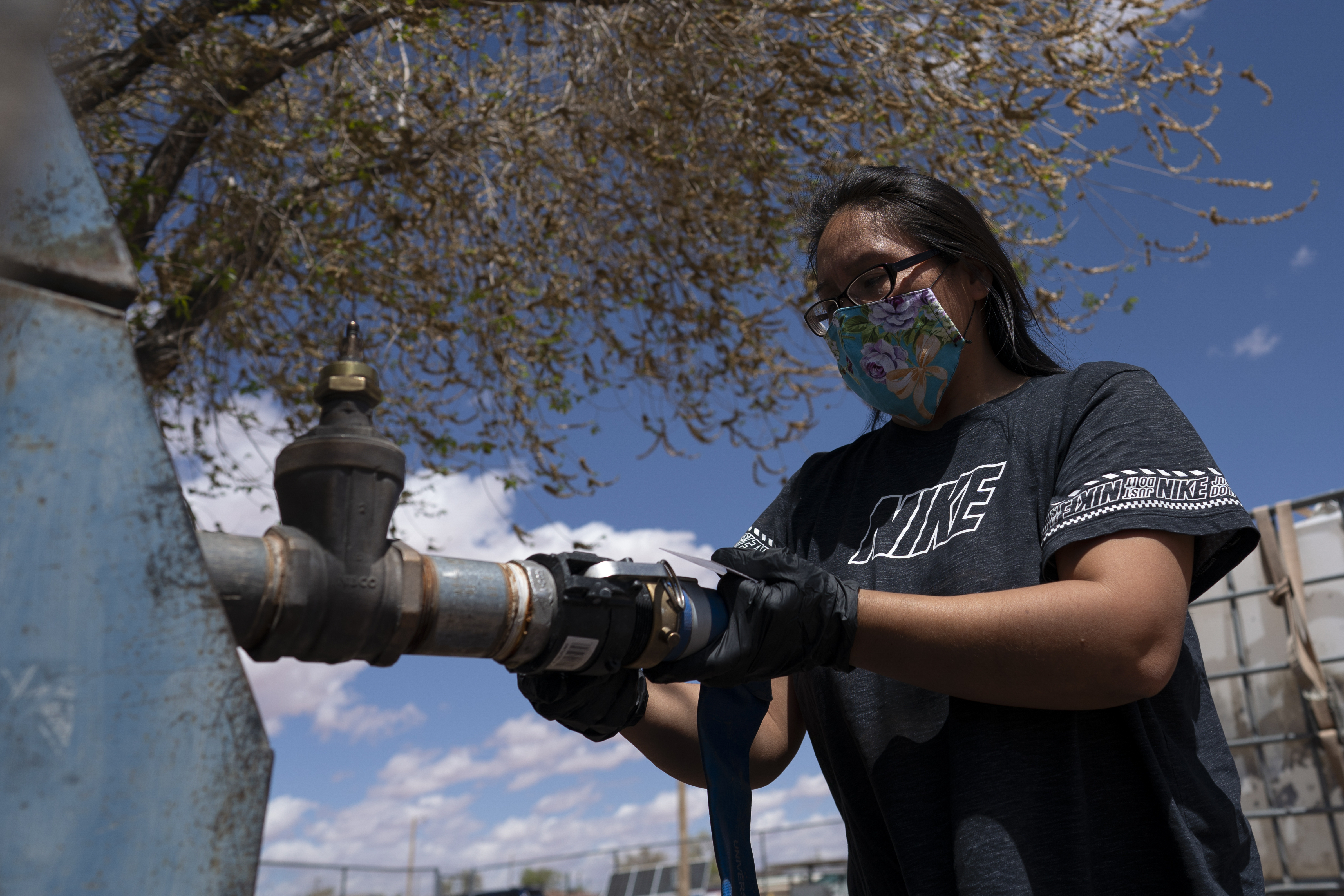 Raynelle Hoskie attaches a hose to a water pump to fill tanks in her truck outside a tribal office on the Navajo reservation in Tuba City, Ariz., on April 20, 2020. The Supreme Court appears to be split in a dispute between the federal government and the Navajo Nation over water from the drought-stricken Colorado River.