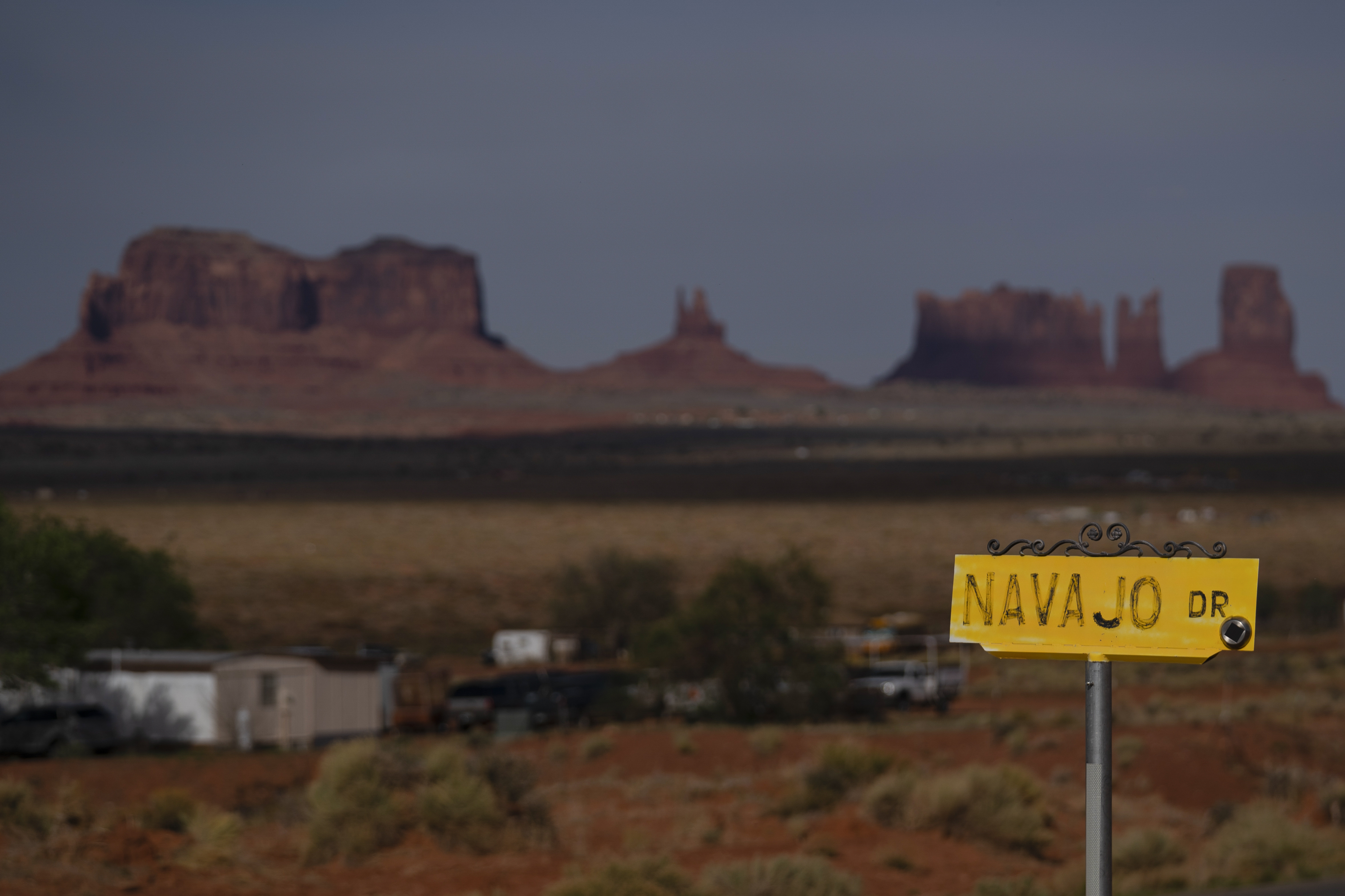 A sign marks Navajo Drive, as Sentinel Mesa, homes and other structures in Oljato-Monument Valley on the Navajo Reservation, stand in the distance, on April 30, 2020. The tribe was recently approved for federal aid for flood damage. 