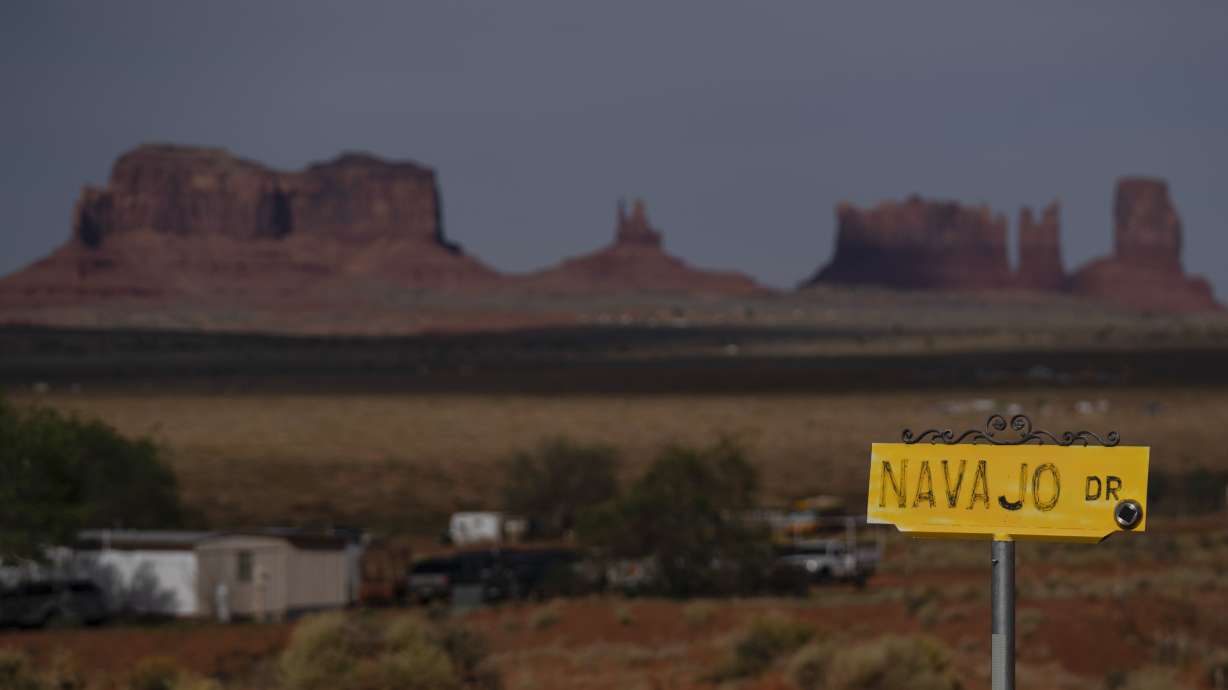 A sign marks Navajo Drive, as Sentinel Mesa, homes and other structures in Oljato-Monument Valley on the Navajo Reservation, stand in the distance, on April 30, 2020. The tribe was recently approved for federal aid for flood damage.