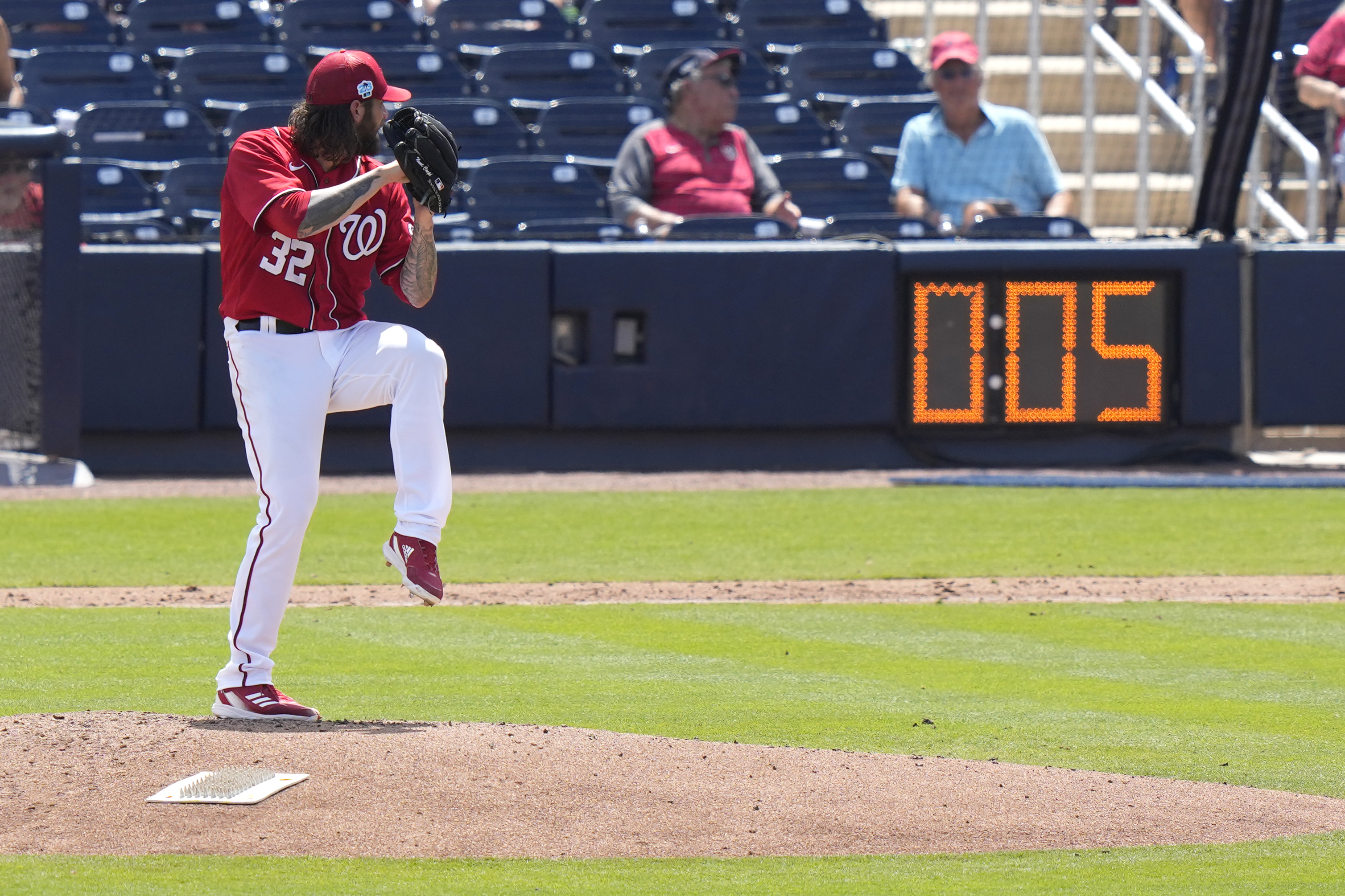 Washington Nationals starting pitcher Trevor Williams (32) winds up to throw as the pitch clock runs during the fourth inning of a spring training baseball game against the Miami Marlins, Saturday, March 18, 2023, in West Palm Beach, Fla.