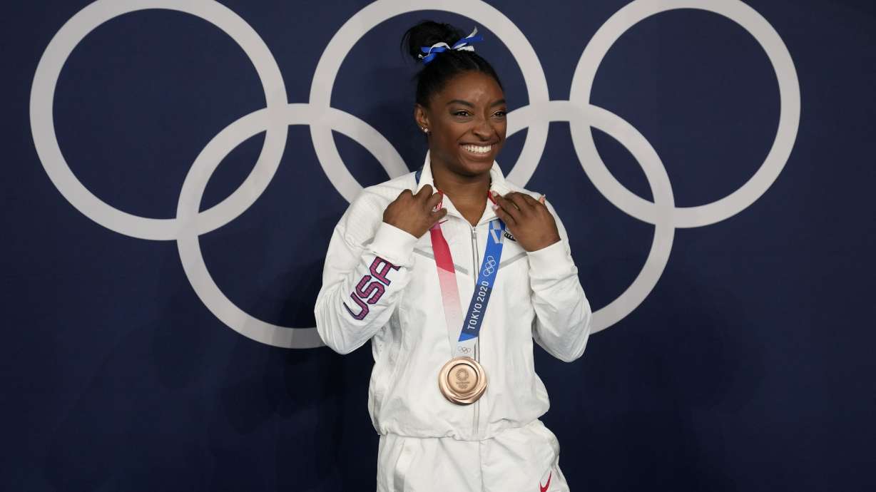 FILE - Simone Biles, of the United States, poses wearing her bronze medal from balance beam competition during artistic gymnastics at the 2020 Summer Olympics, Tuesday, Aug. 3, 2021, in Tokyo, Japan. The sport of gymnastics' international investigations agency was created in 2019 to help protect athletes after the American sexual abuse scandal. The Gymnastics Ethics Foundation has now published its strategy to set new standards in safeguarding before the 2028 Los Angeles Olympics. The “Gymnasts 2028” details goals for its work to protect athletes from harassment and abuse, investigate complaints, prosecute disciplinary cases and monitor national federations.
