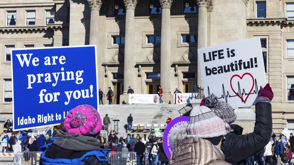 People walk to the Idaho Capitol Building carrying signs for the Boise March for Life rally, June 21, 2022.