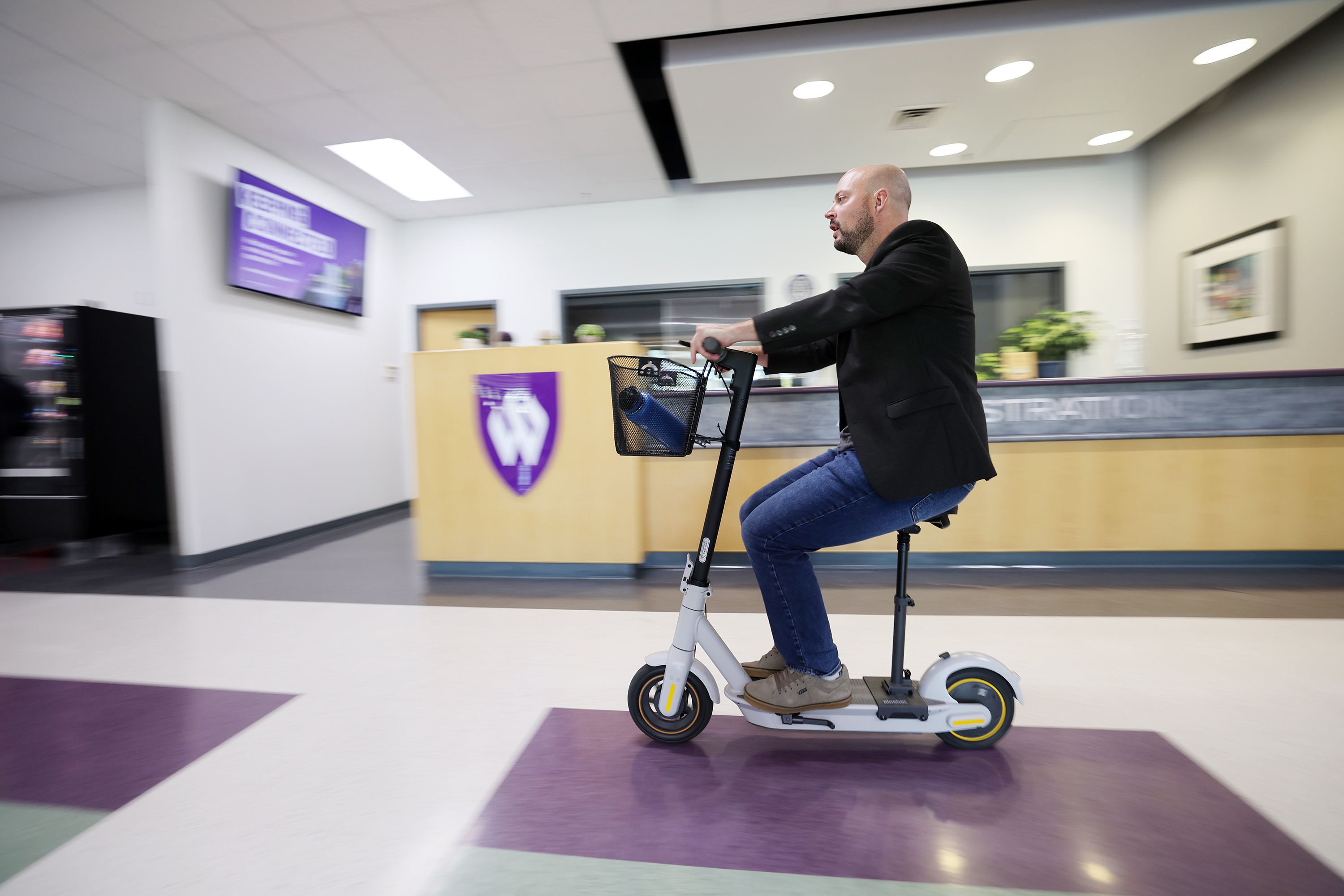 Blake Bockholt, a high school teacher at NUAMES High School at the Weber State Layton campus, rides a scooter back to his class after filling his water bottle on Oct. 4, 2022. Bockholt suffers from long COVID-19.