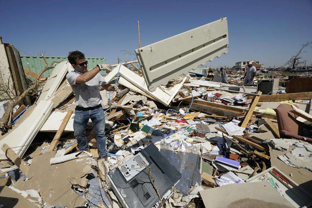 Charlie Weissinger, tosses away the paneling from one of the desks in his father's demolished law office in Rolling Fork, Mississippi, Saturday.