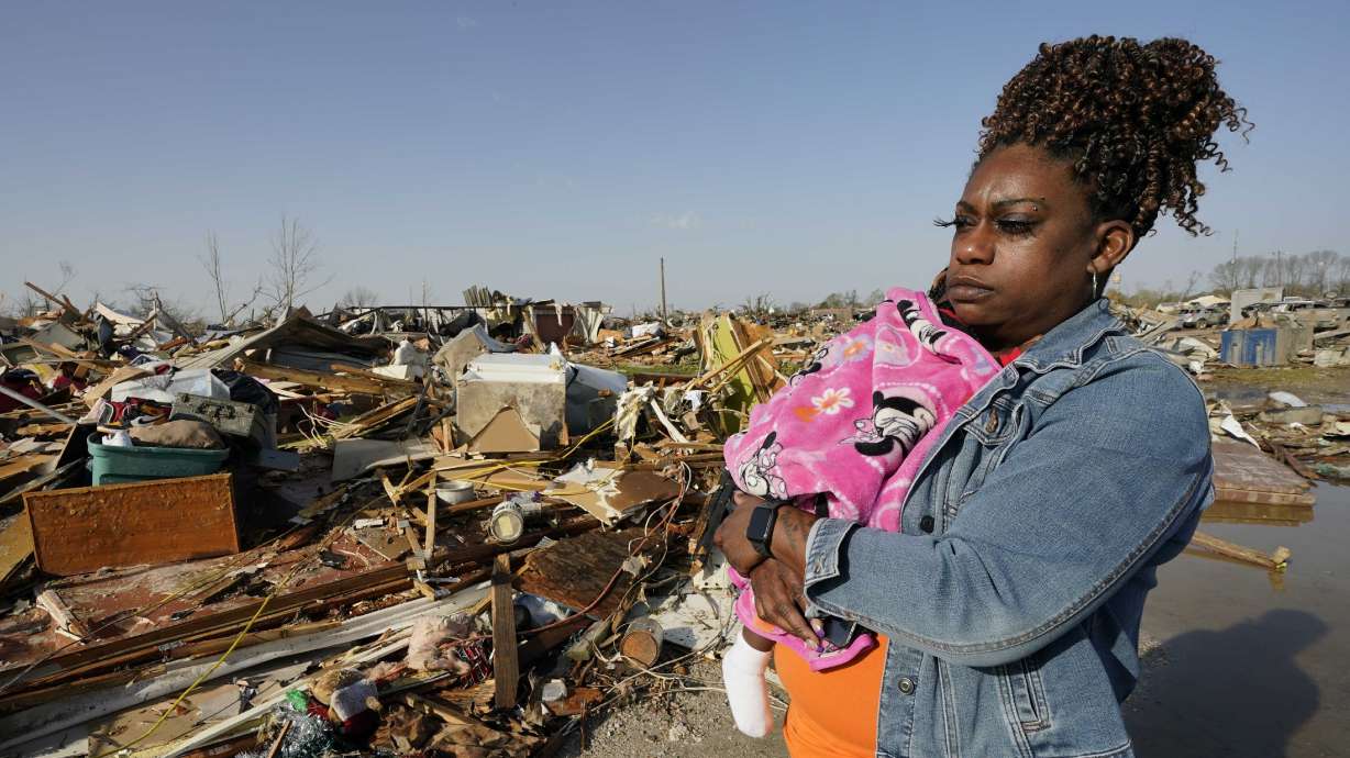 Wonder Bolden cradles her year-old granddaughter Journey Bolden as she surveys the remains of her mother's tornado-demolished mobile home in Rolling Fork, Miss., Saturday.