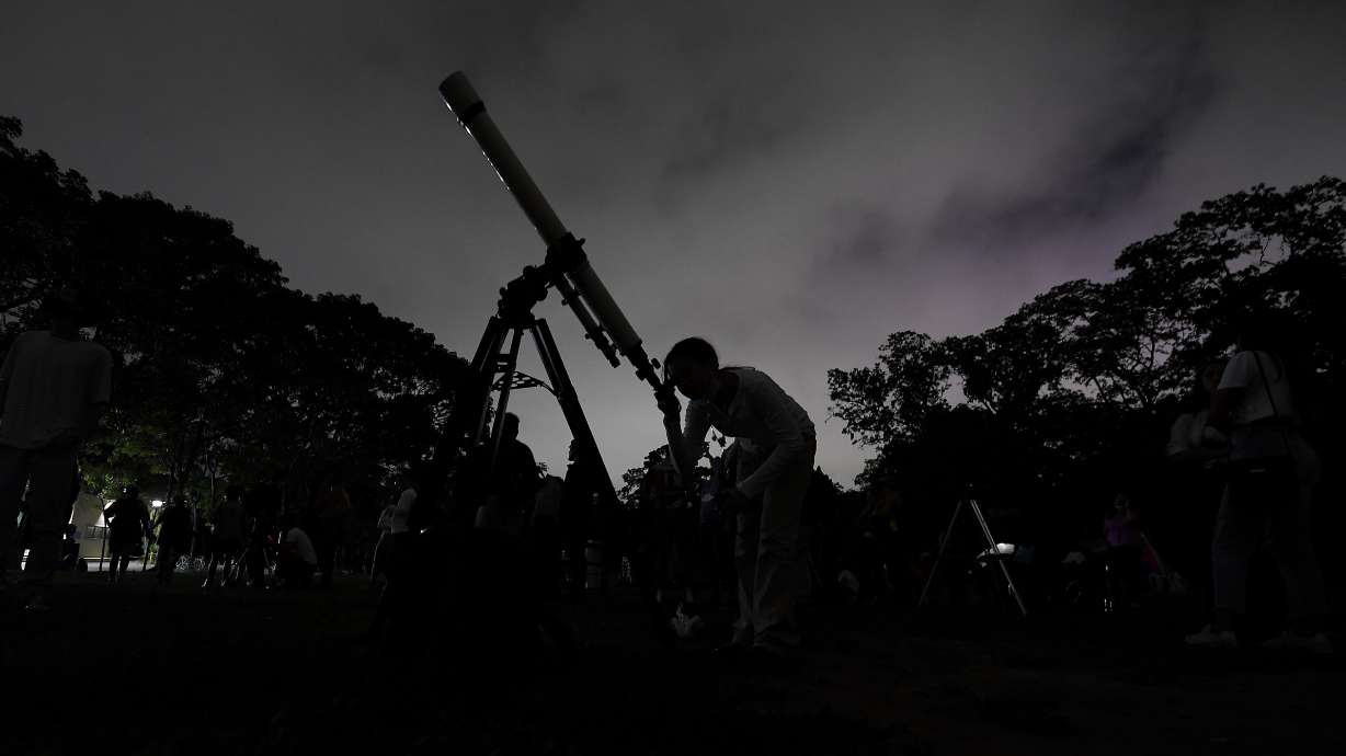 A girl looks at the moon through a telescope in Caracas, Venezuela, on May 15, 2022. The best day to spot five planets, Mercury, Jupiter, Venus, Uranus and Mars, lined up in the night sky is Tuesday, right after sunset.