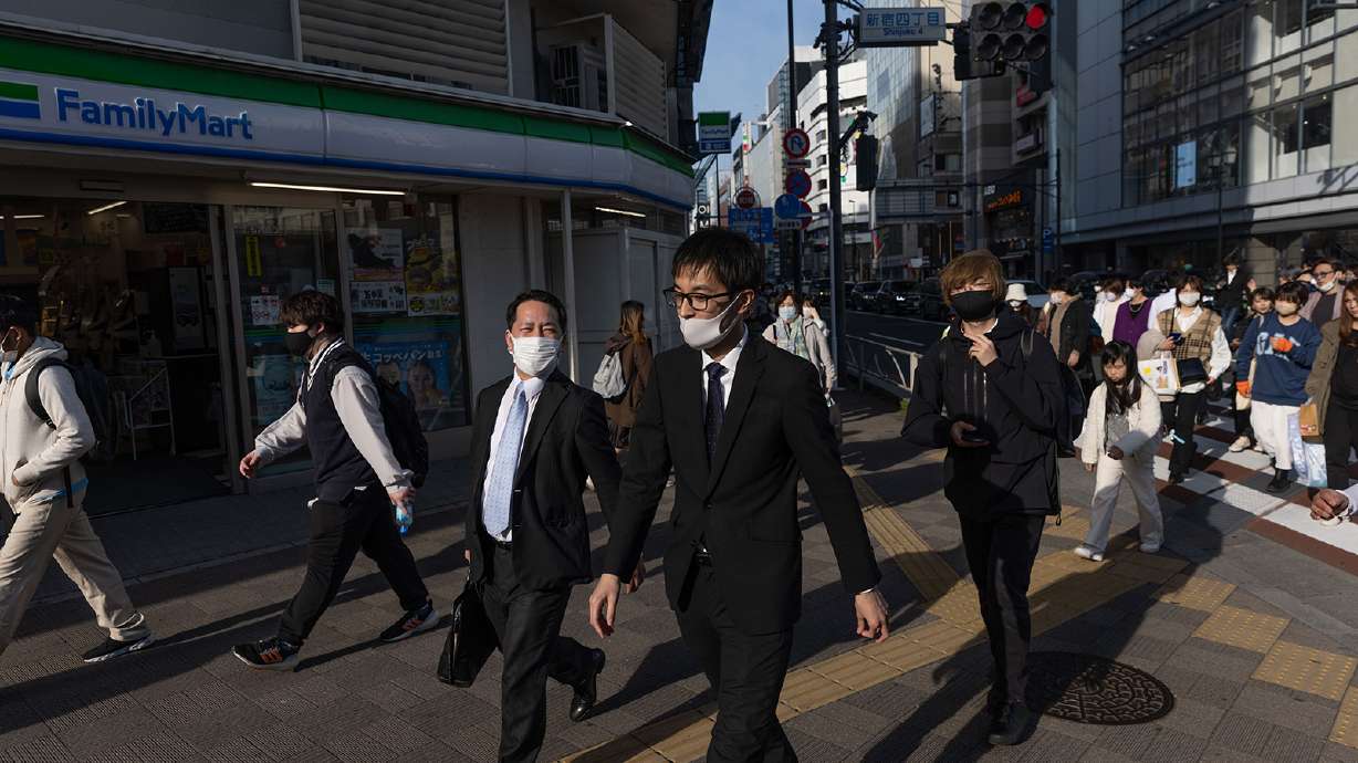 Businessmen walk towards Shinjuku station in Tokyo on March 16. Men who have the option to take paternity leave are hesitant to take it.