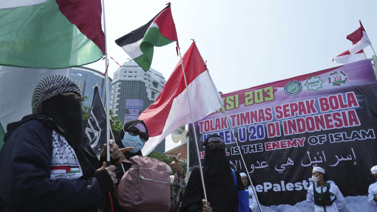 Protesters wave Palestinian flag during a protest in Jakarta, Indonesia, Monday, March 20, 2023. Hundreds of conservative Muslims have marched to the streets Monday in Indonesia's capital to protest against the Israeli team's participation in the FIFA World Cup Under-20 in Indonesia.