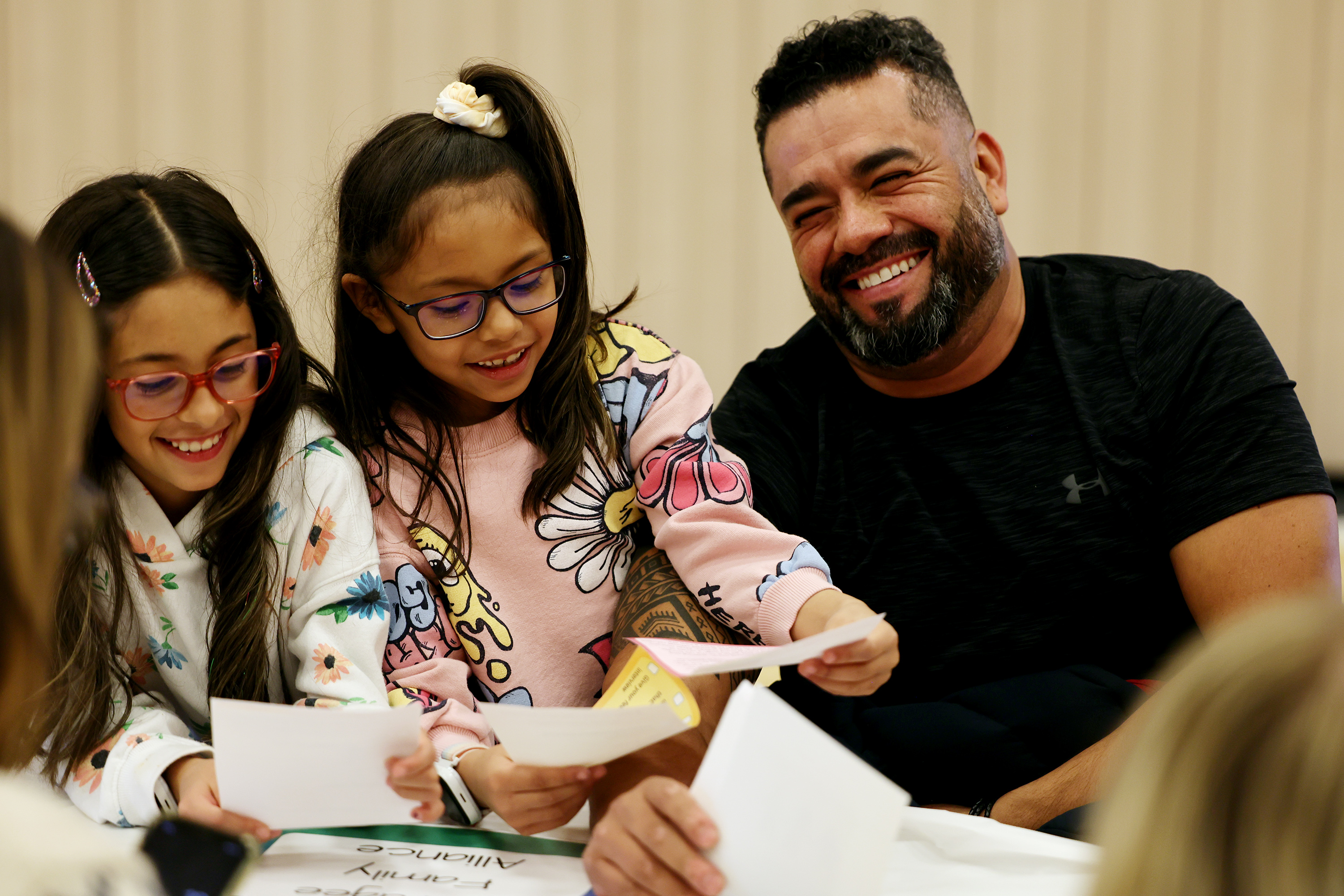 Elizabeth and Aileen Reyes laugh with their dad Carlos as they learn about what it’s like for refugees at "A day in the life of a refugee" event in Lehi on Friday.