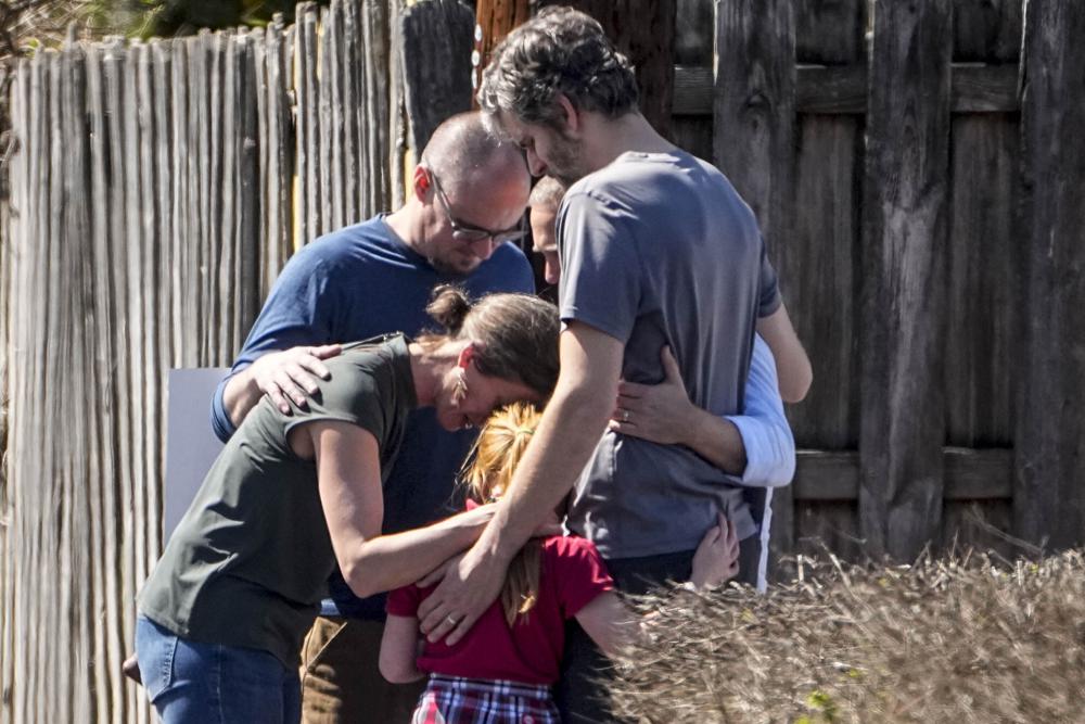 A group prays with a child outside the reunification center at the Woodmont Baptist church after a school shooting, Monday in Nashville, Tenn.