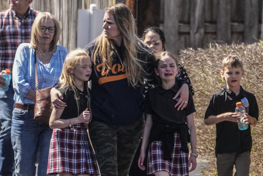 Children and a woman depart the reunification center at the Woodmont Baptist church after a school shooting, Monday in Nashville, Tennessee.