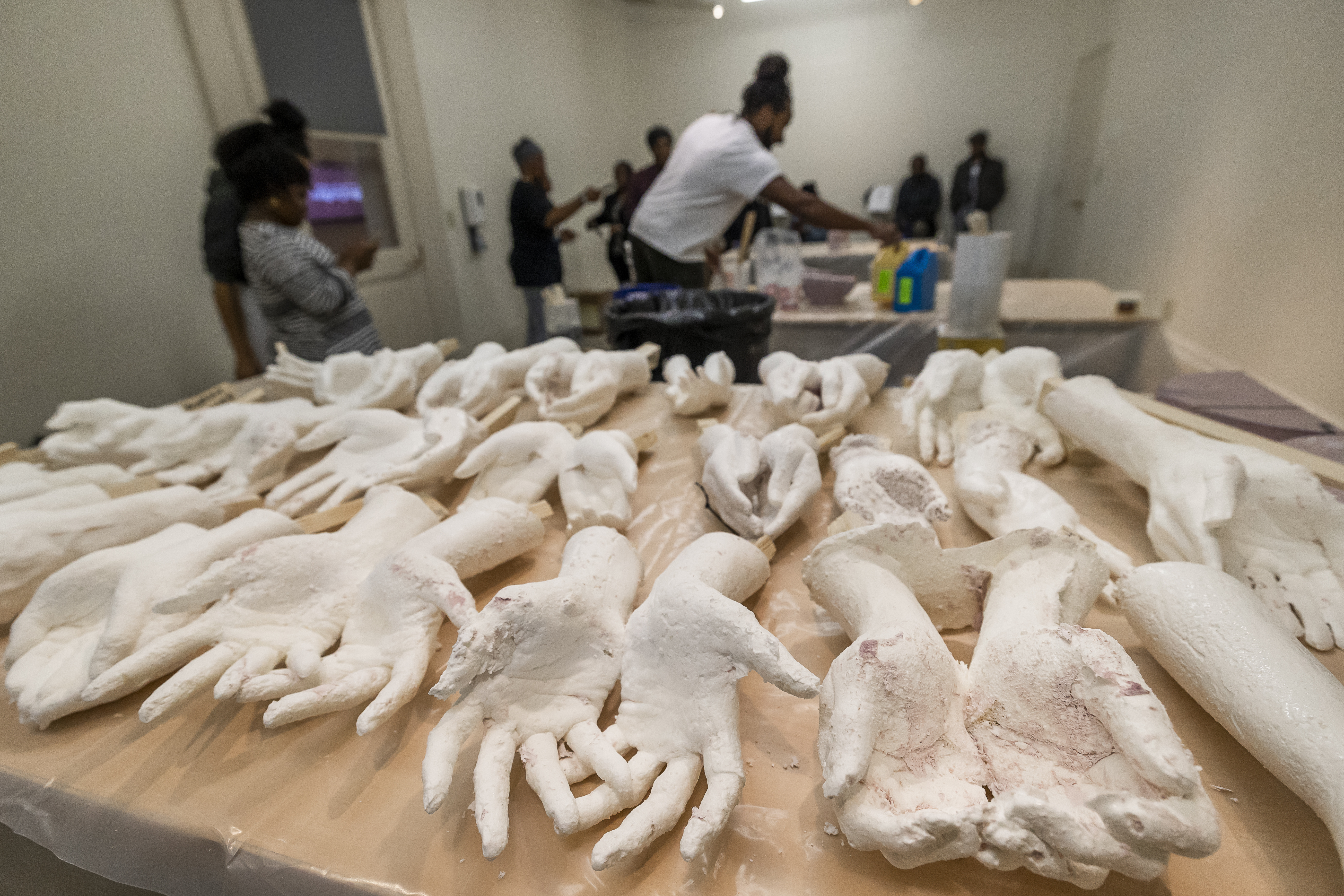 Cast hands made from local volunteers are displayed on a table in Charleston, S.C., Feb. 18. Artist Stephen Hayes, background center, will use the molds to make a memorial for 36 enslaved people whose bodies were unearthed in Charleston in 2013 during a construction project for the Gaillard Center.