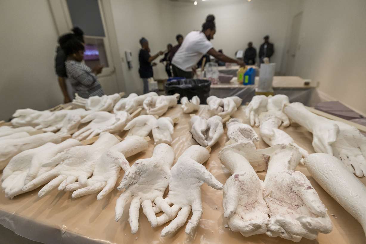 Cast hands made from local volunteers are displayed on a table in Charleston, S.C., Feb. 18. Artist Stephen Hayes, background center, will use the molds to make a memorial for 36 enslaved people whose bodies were unearthed in Charleston in 2013 during a construction project for the Gaillard Center.