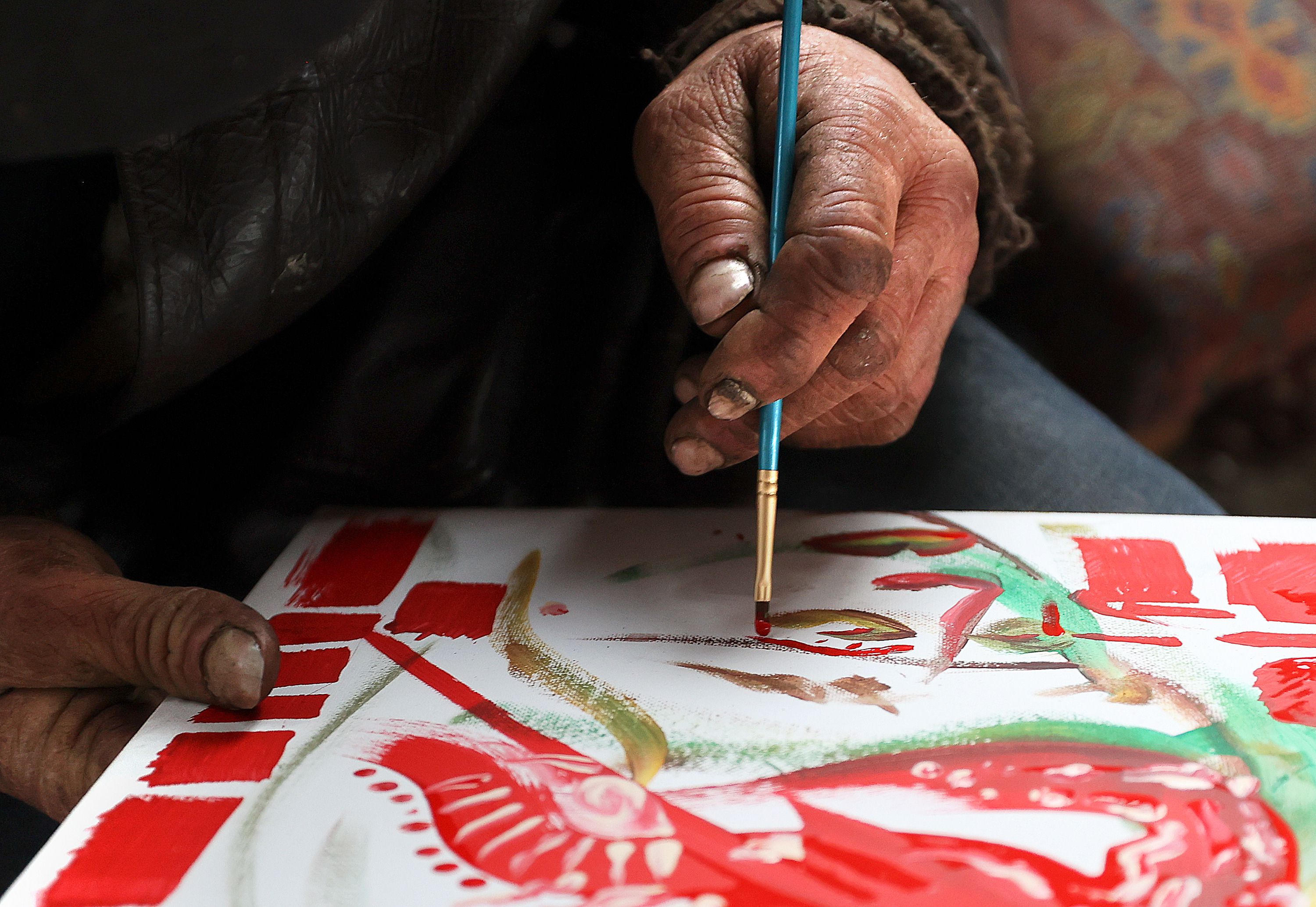 Robert West, who is unsheltered, adds to a communal painting on the Nomad Alliance bus temporarily parked outside a meetinghouse of The Church of Jesus Christ of Latter-day Saints that is not in use in Salt Lake City, on March 8. West, who is 43, has been unsheltered on and off since age 18.